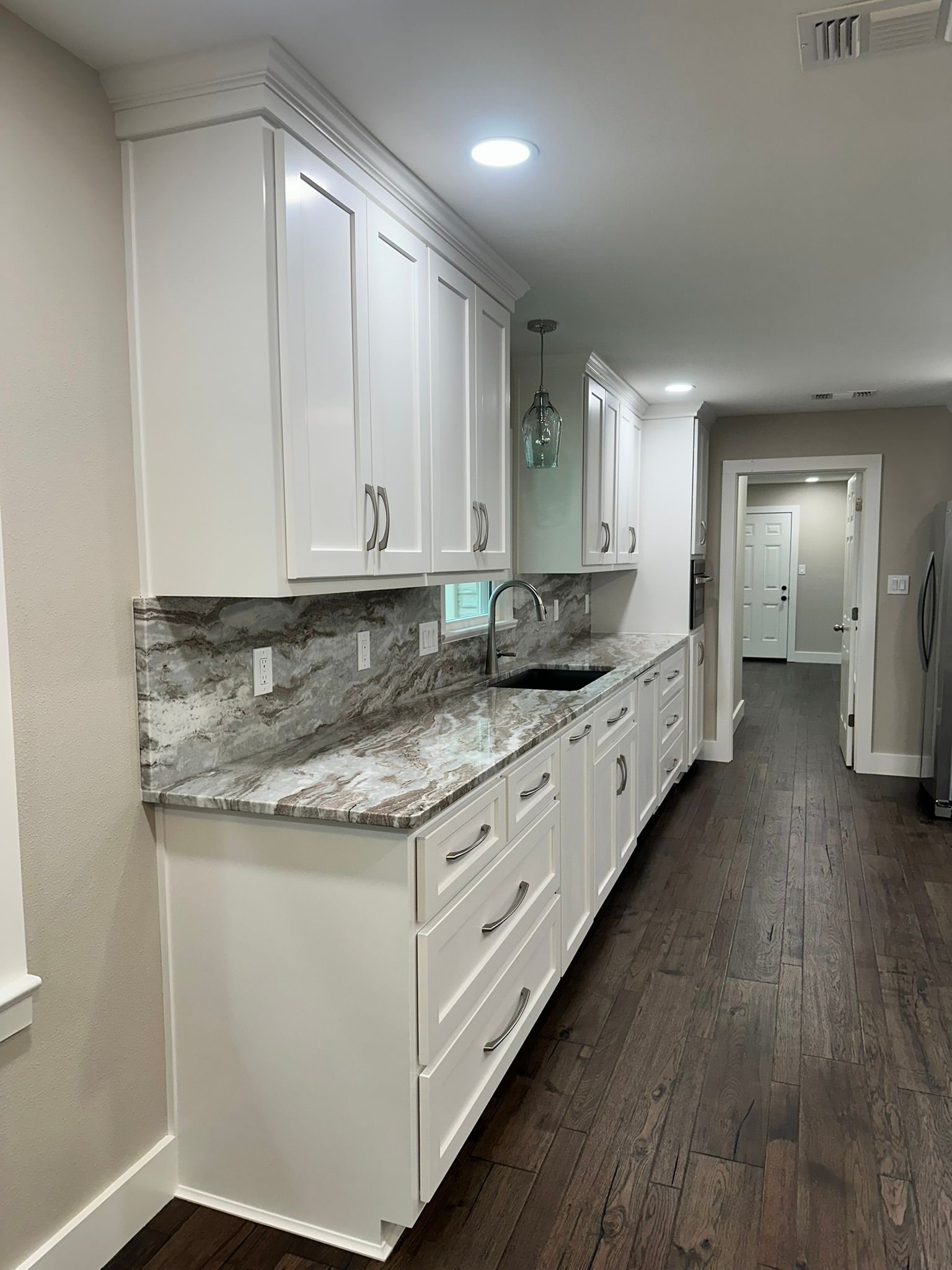 A kitchen with white cabinets and granite counter tops.