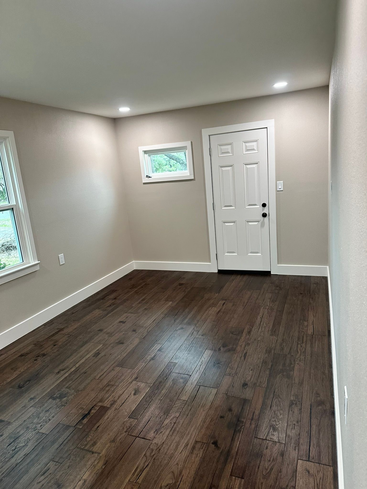 A living room with hardwood floors and a white door.