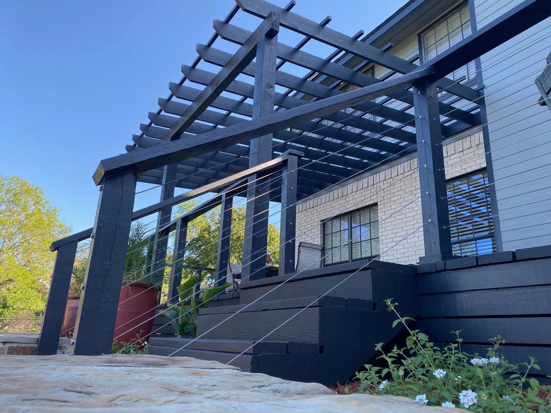 A pergola is sitting on top of a wooden deck next to a house.