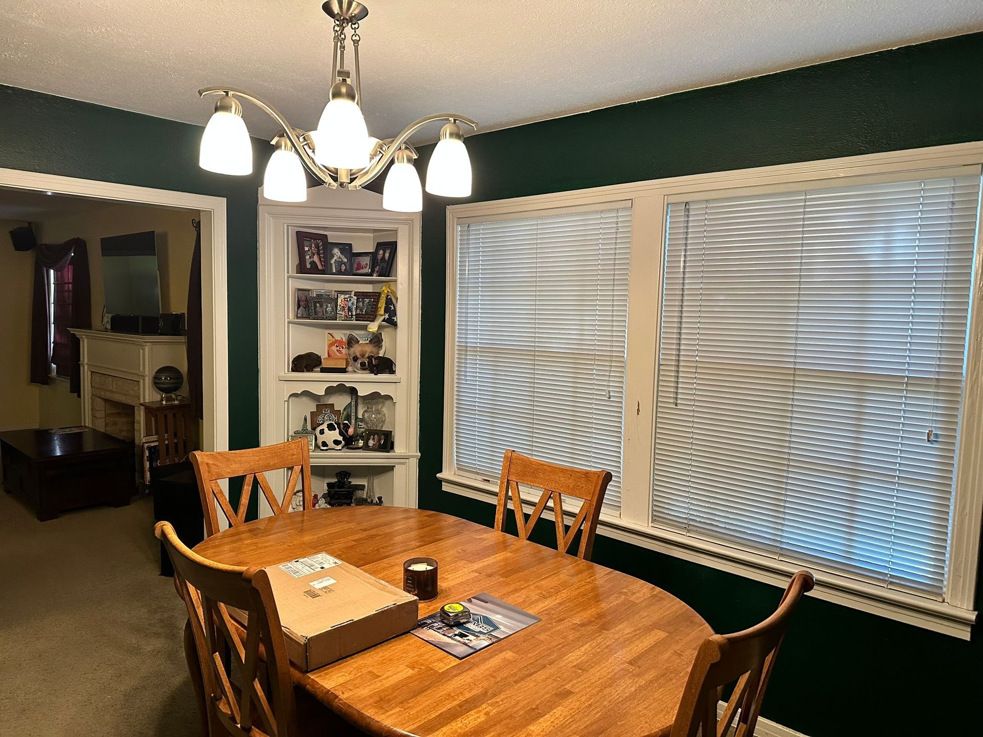 A dining room with a wooden table and chairs and a chandelier.