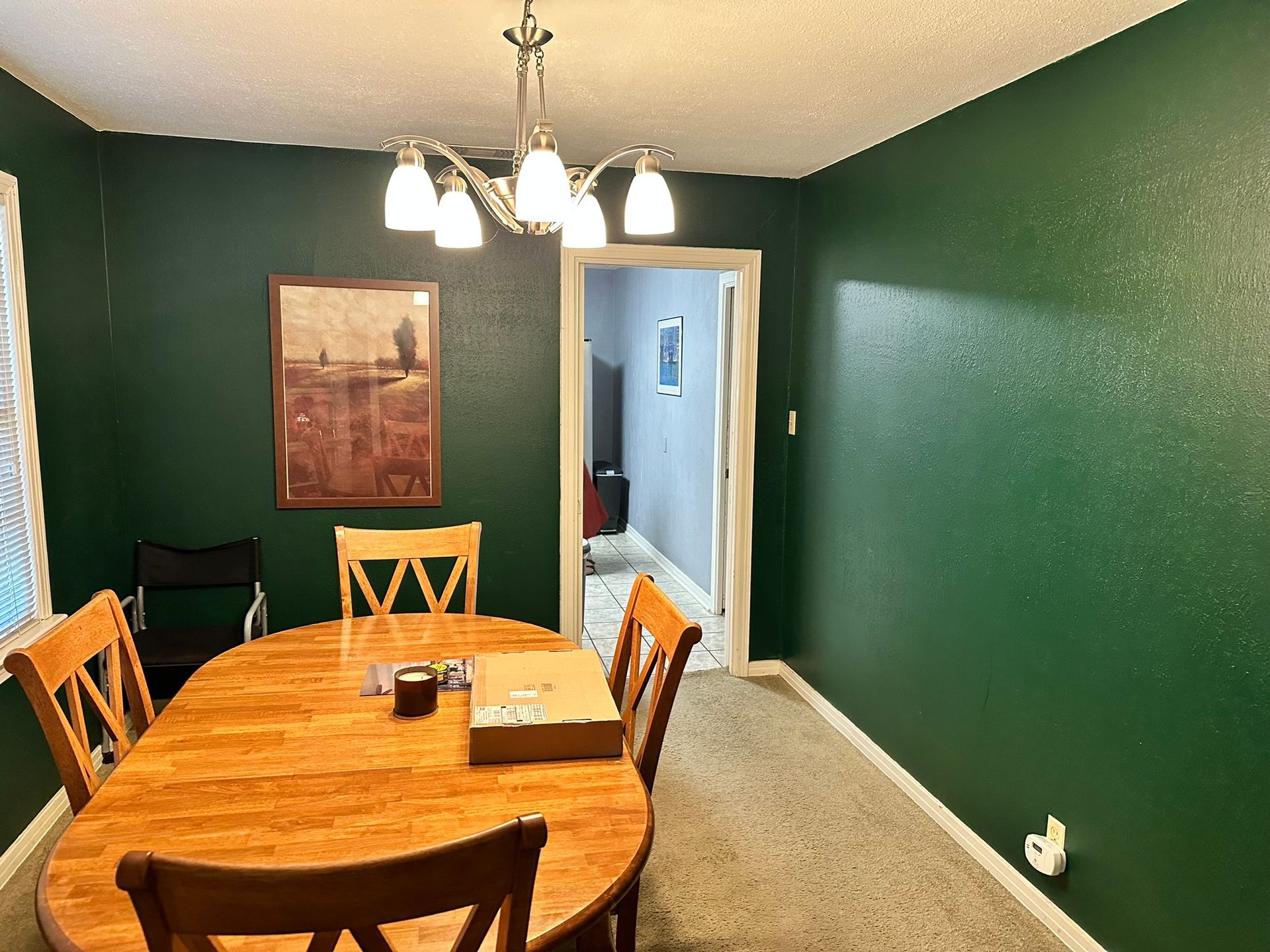 A dining room with green walls and a wooden table and chairs