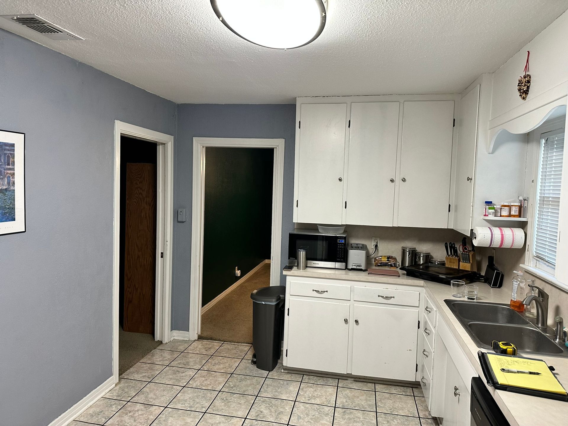 A kitchen with white cabinets and a sink