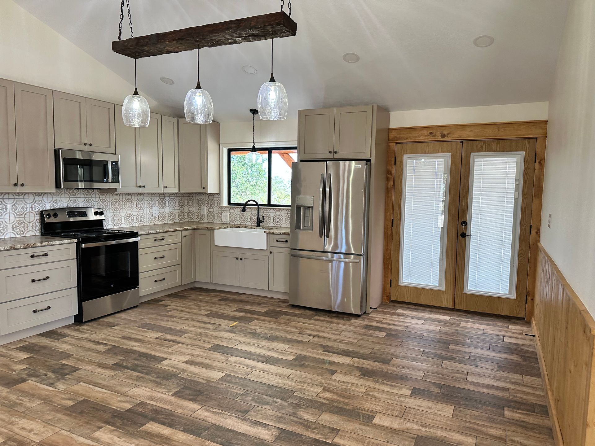 A kitchen with stainless steel appliances and wooden floors.