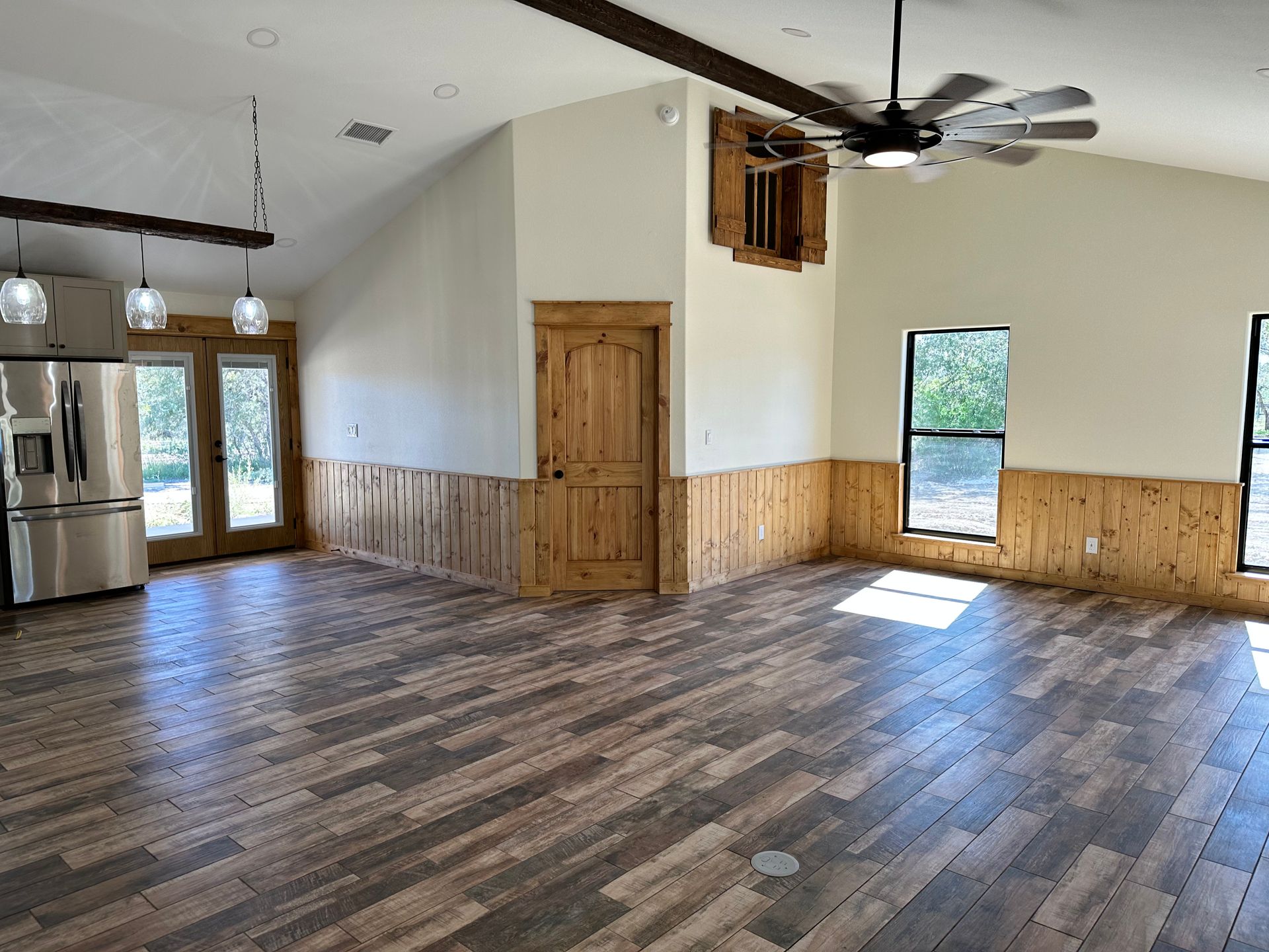 A large empty room with wooden floors and a ceiling fan.