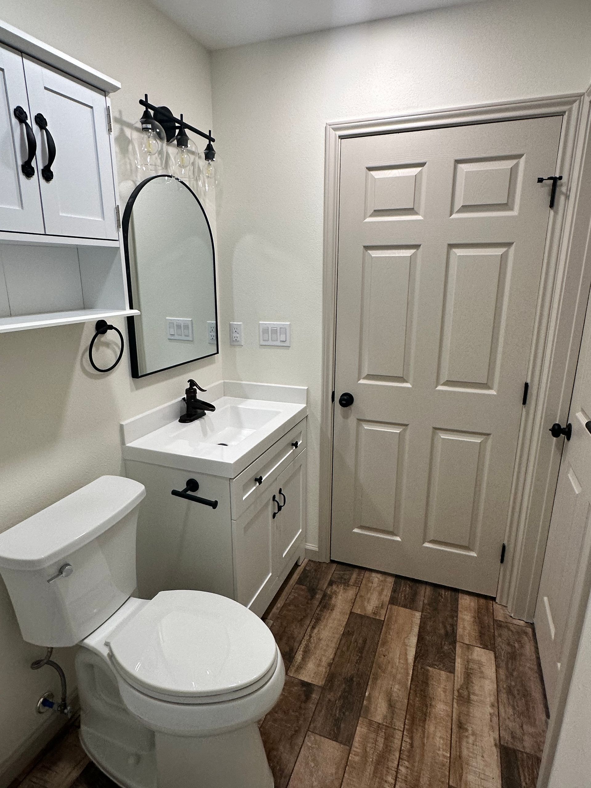 A bathroom with a toilet , sink and mirror.