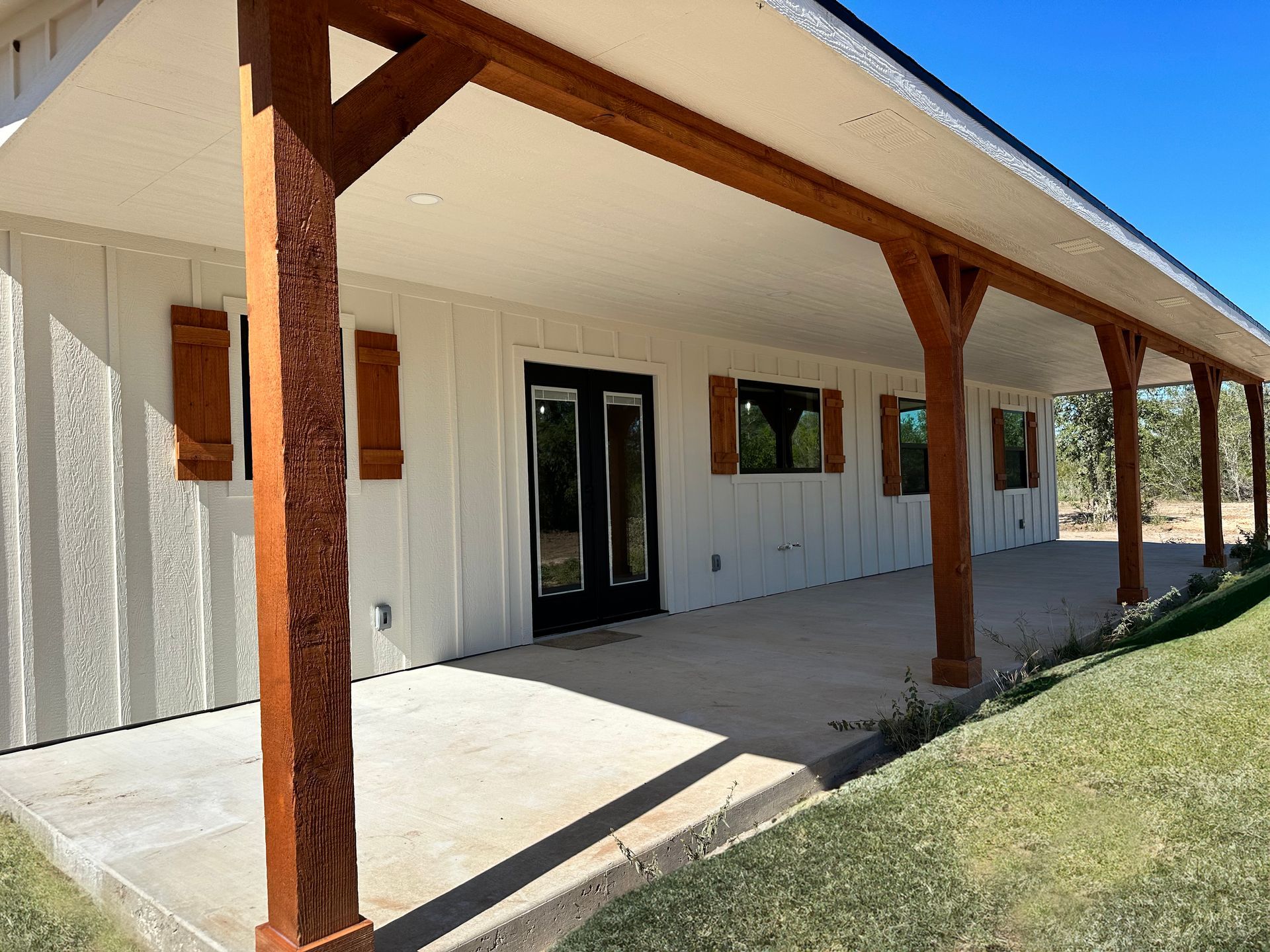 A white house with a covered porch and wooden posts