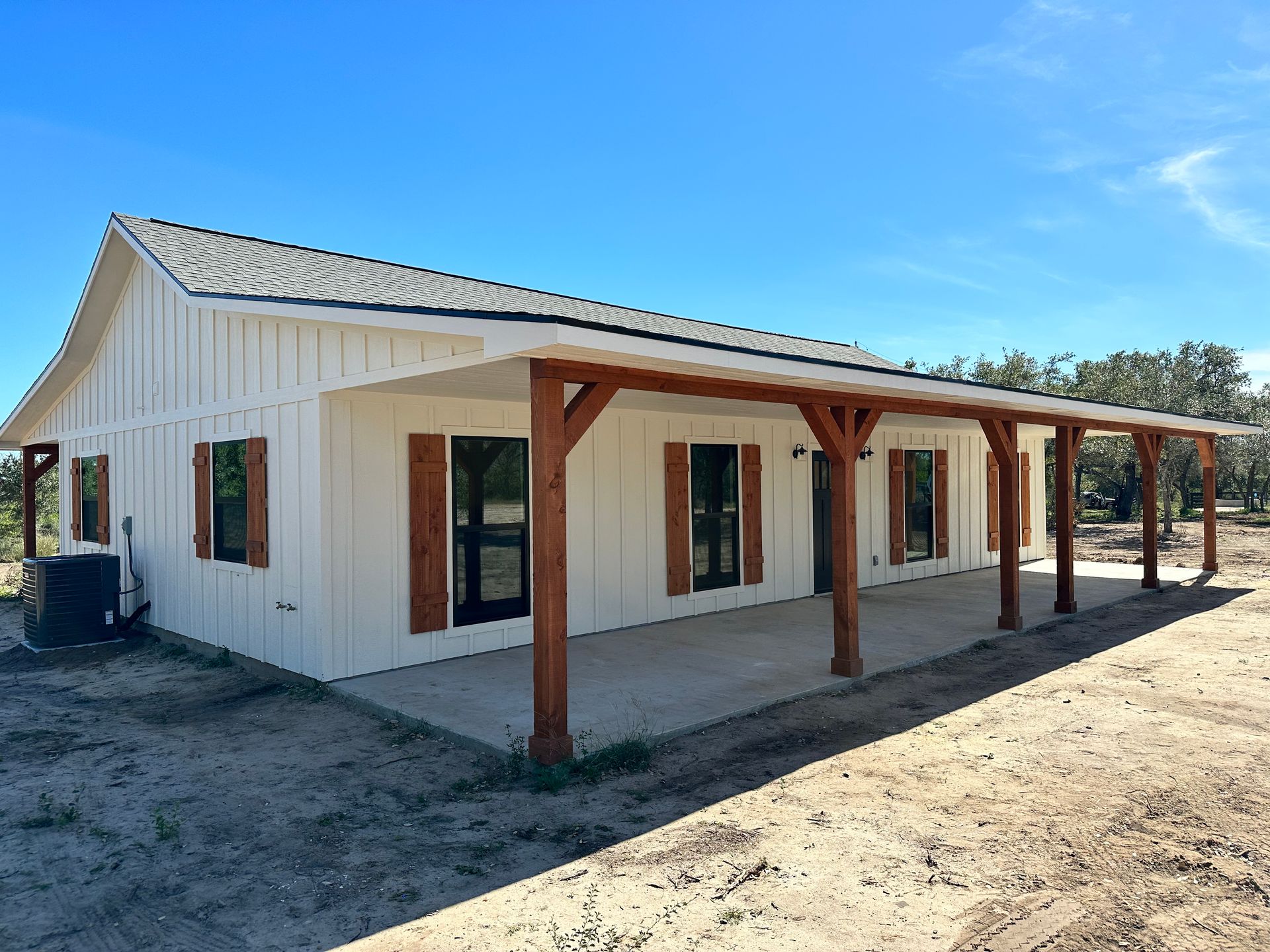 A white house with a porch and shutters on the windows.