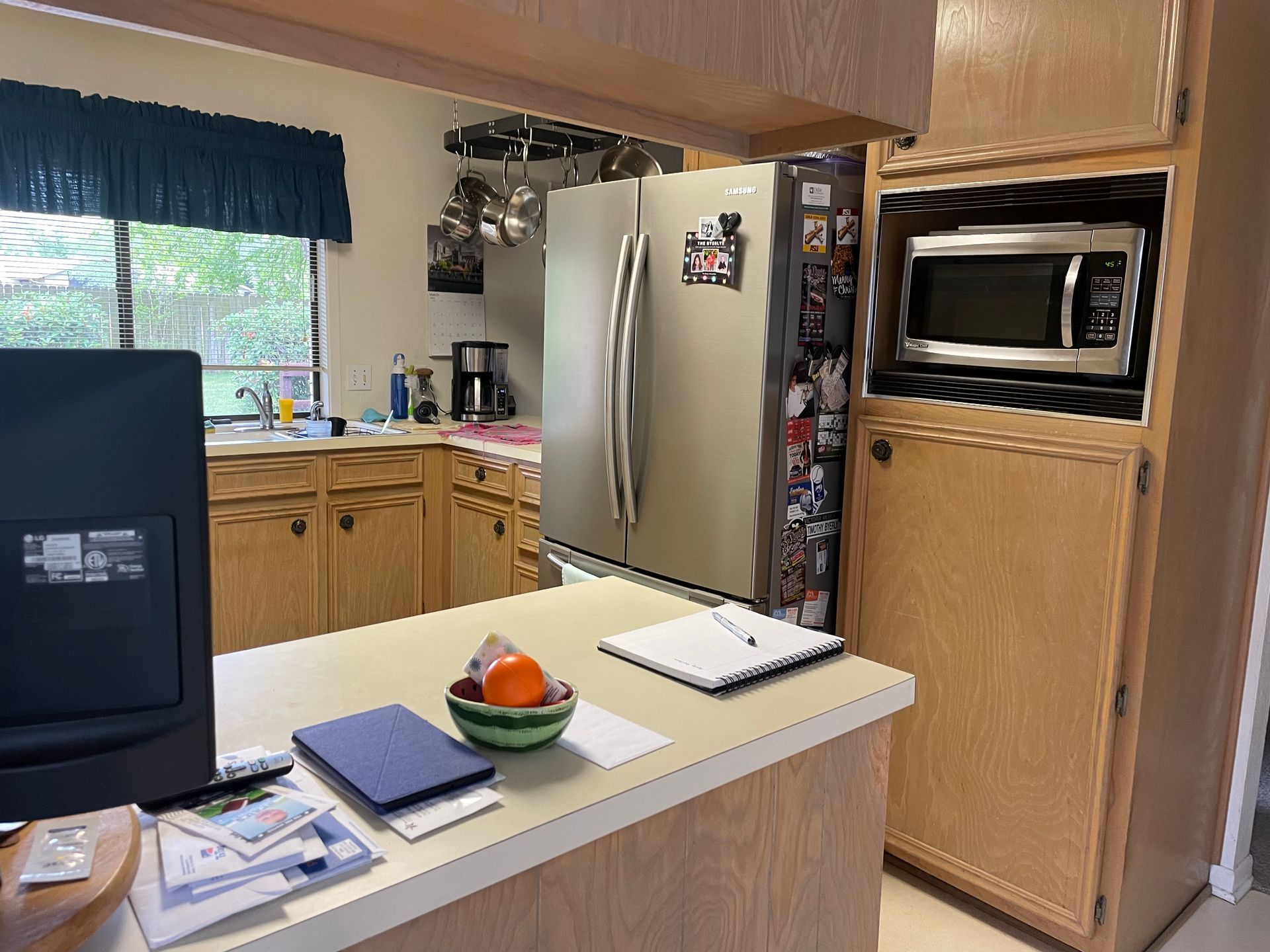 A kitchen with a stainless steel refrigerator and a microwave