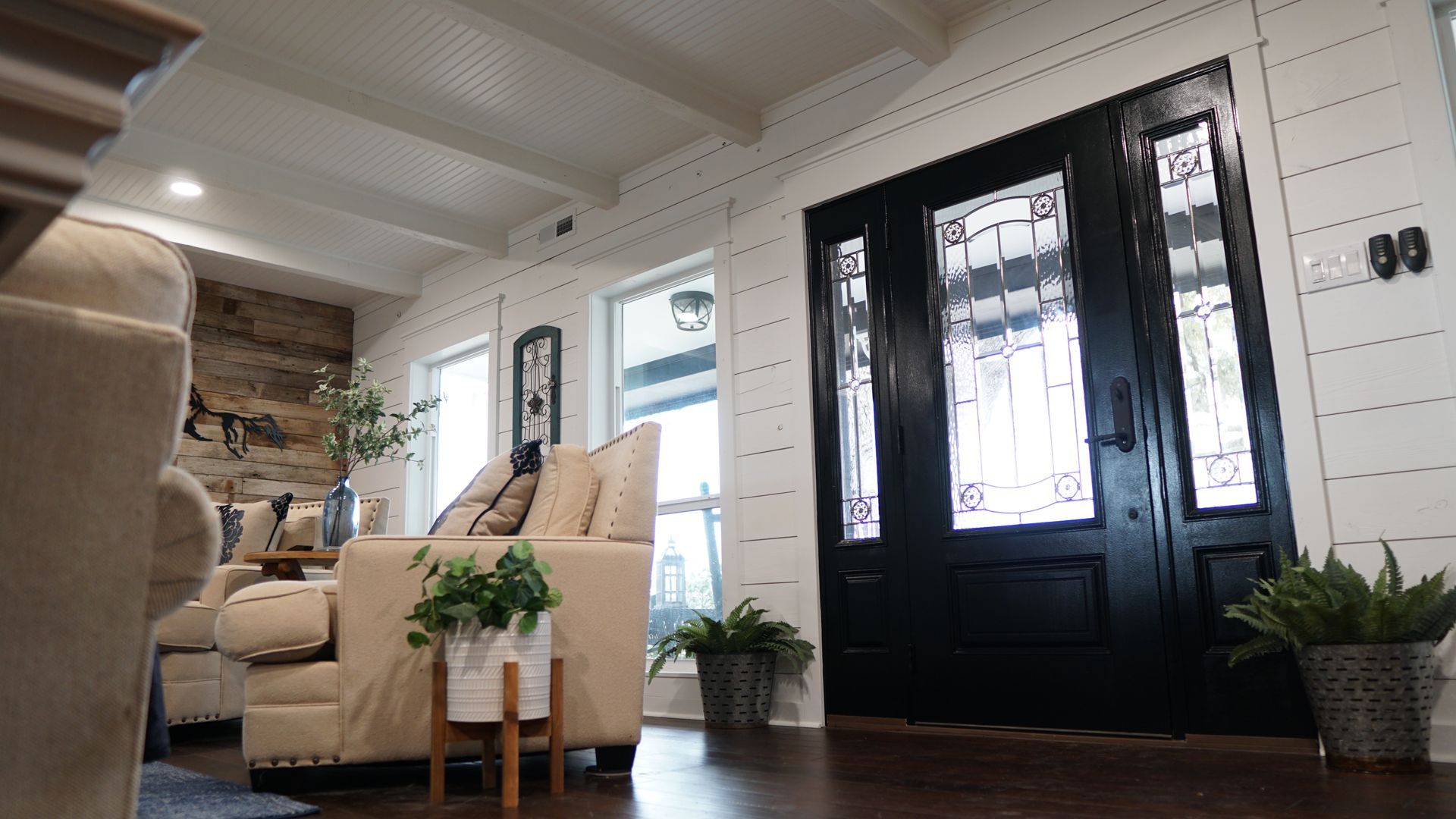 A living room with a couch , chairs , and a black door.