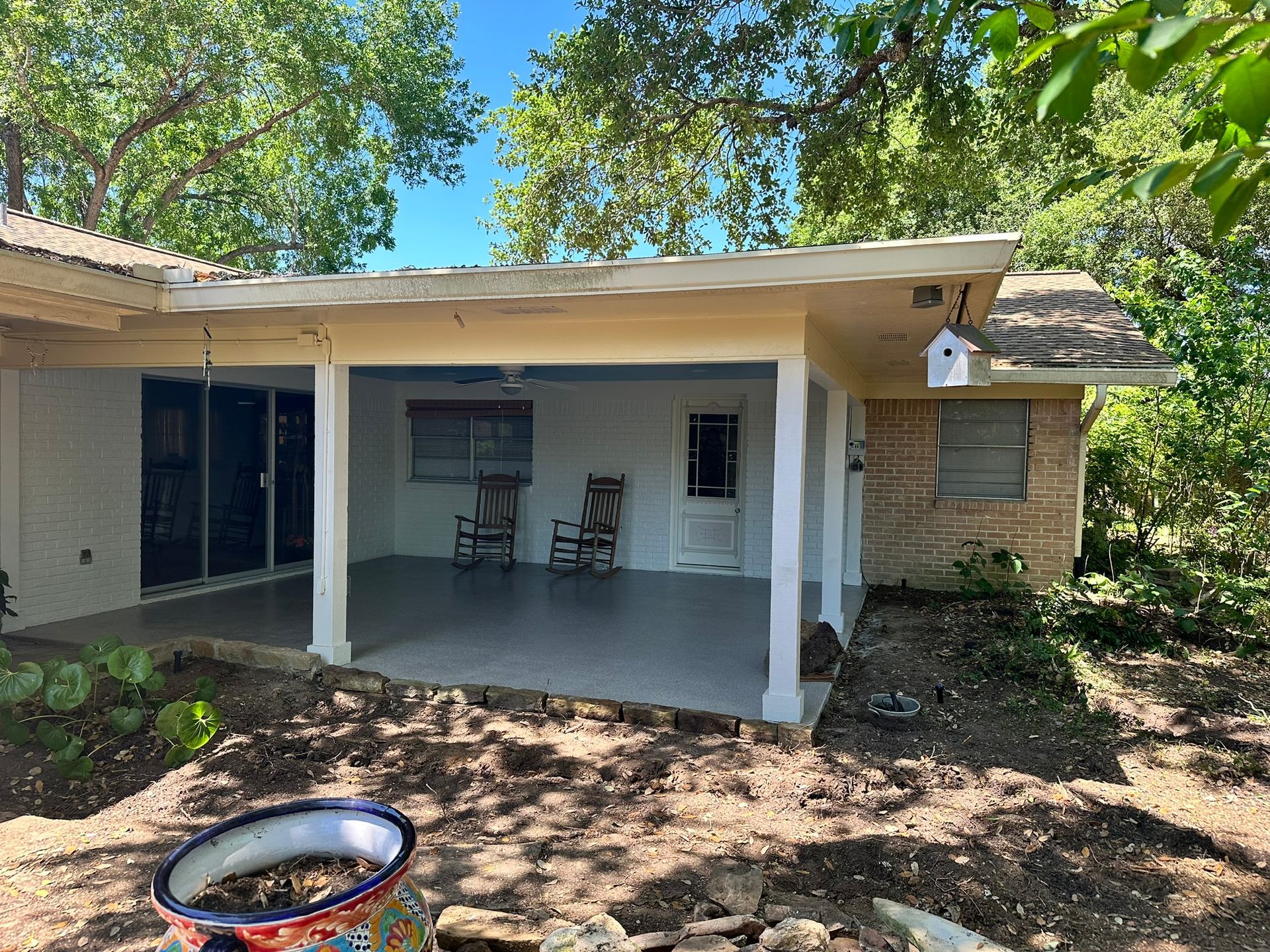 A white house with a covered porch and rocking chairs.