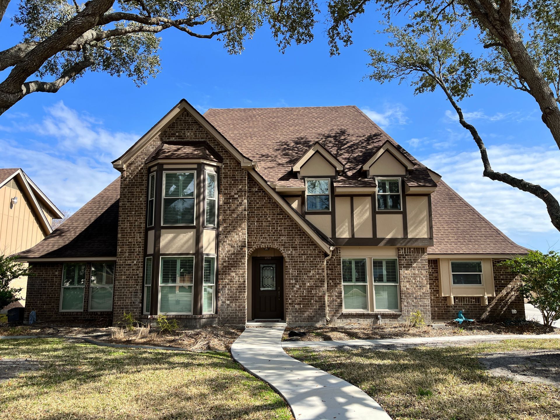 A large brick house with a brown roof and many windows