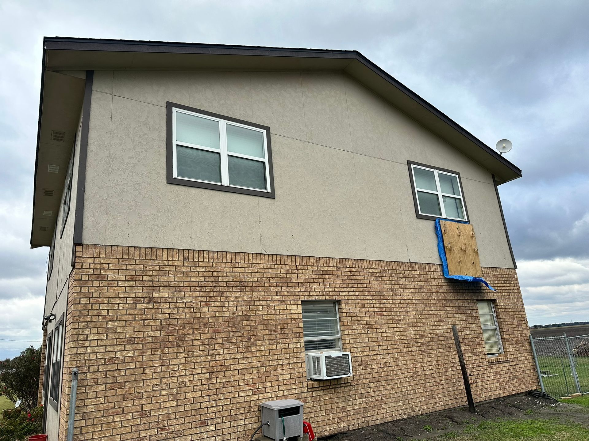A brick house with a blue tarp on the side of it.