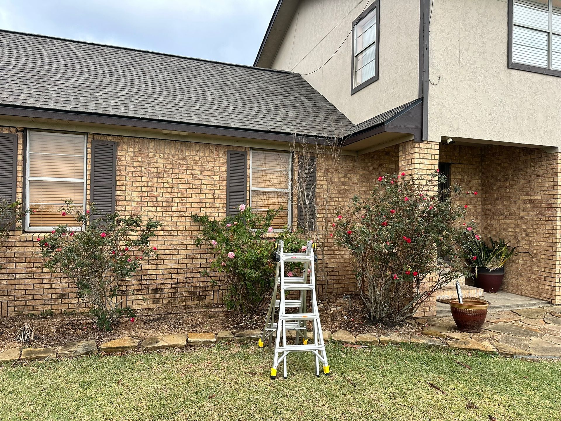 A ladder is sitting in front of a brick house.