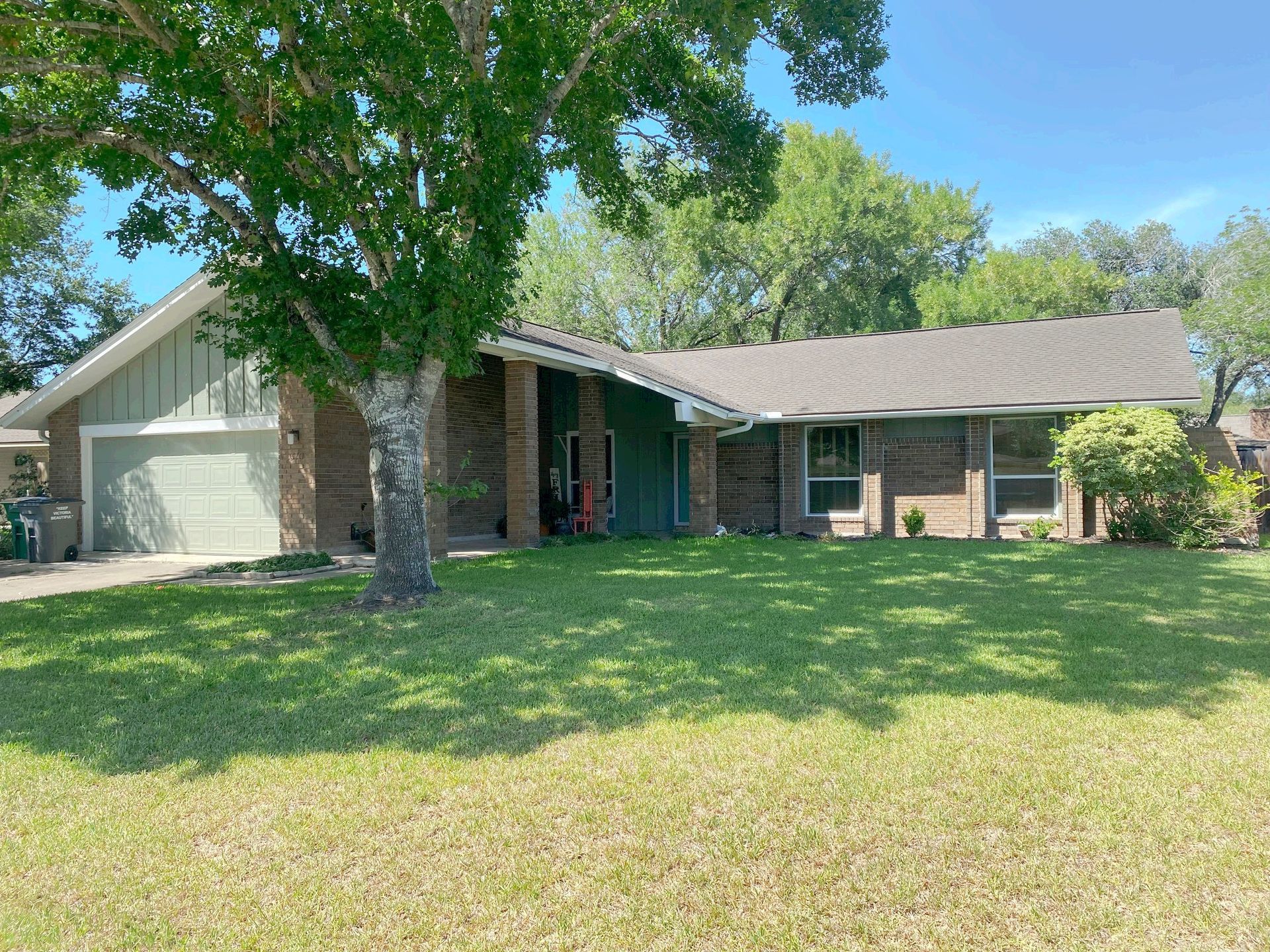 A brick house with a large lawn in front of it.