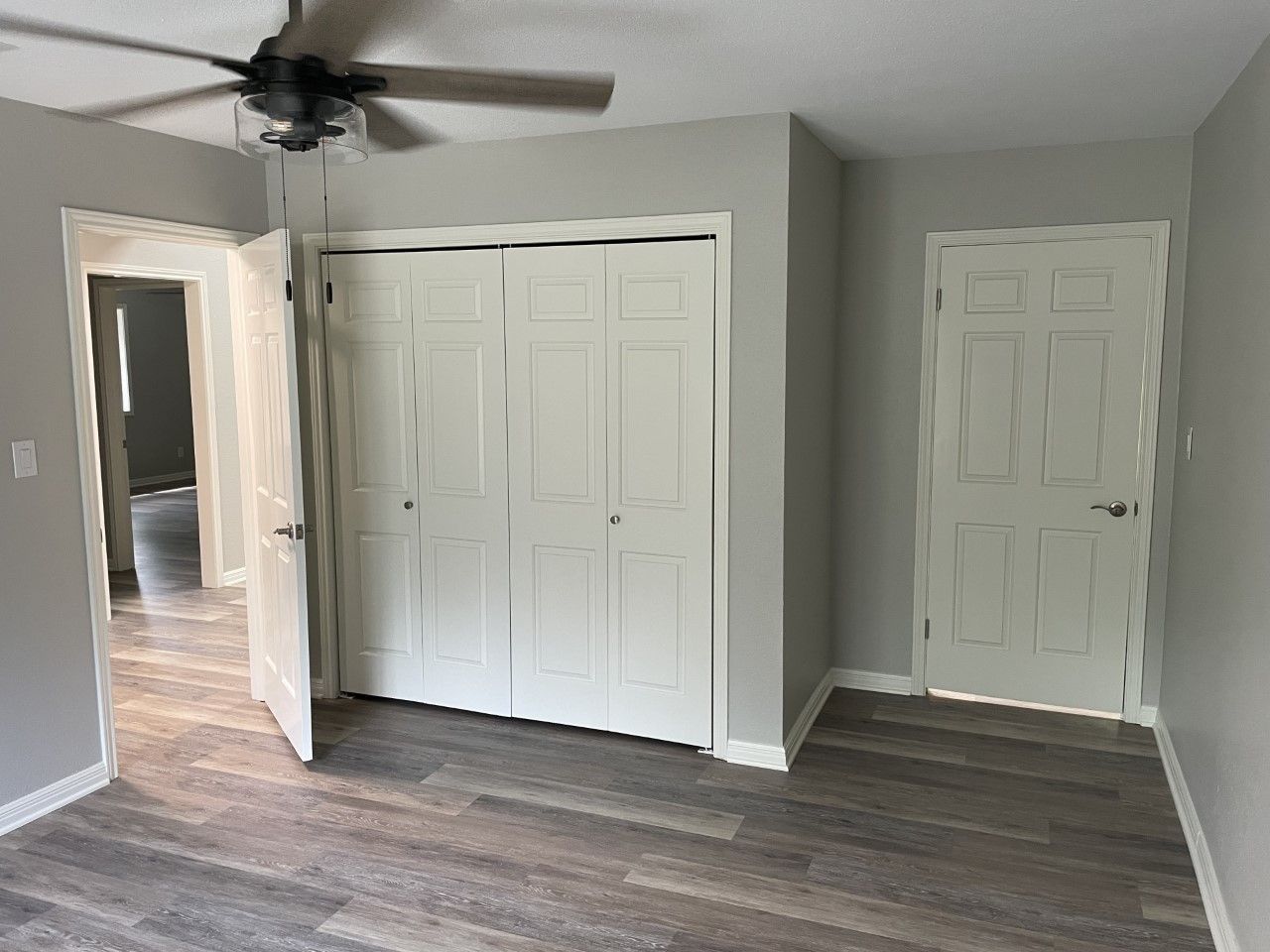 A bedroom with a ceiling fan and a closet.