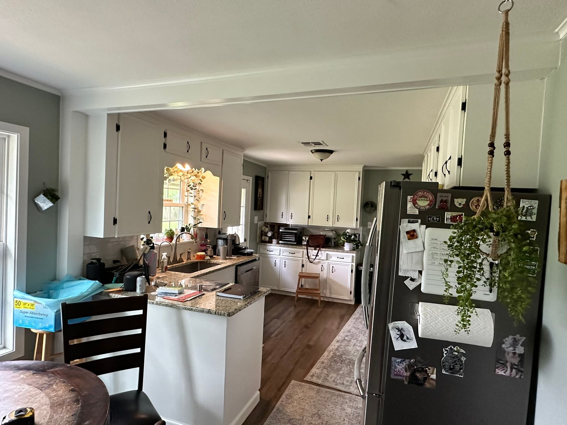 A kitchen with white cabinets and a black refrigerator.