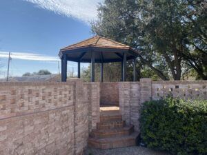 A gazebo with stairs leading up to it is surrounded by a brick wall.