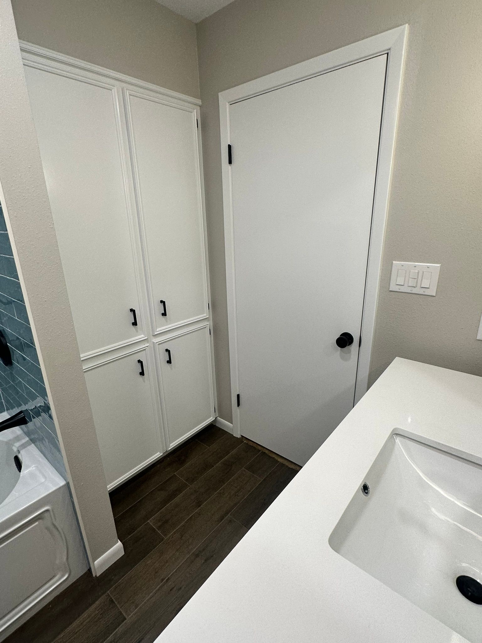 A bathroom with a sink , cabinets , and a door.