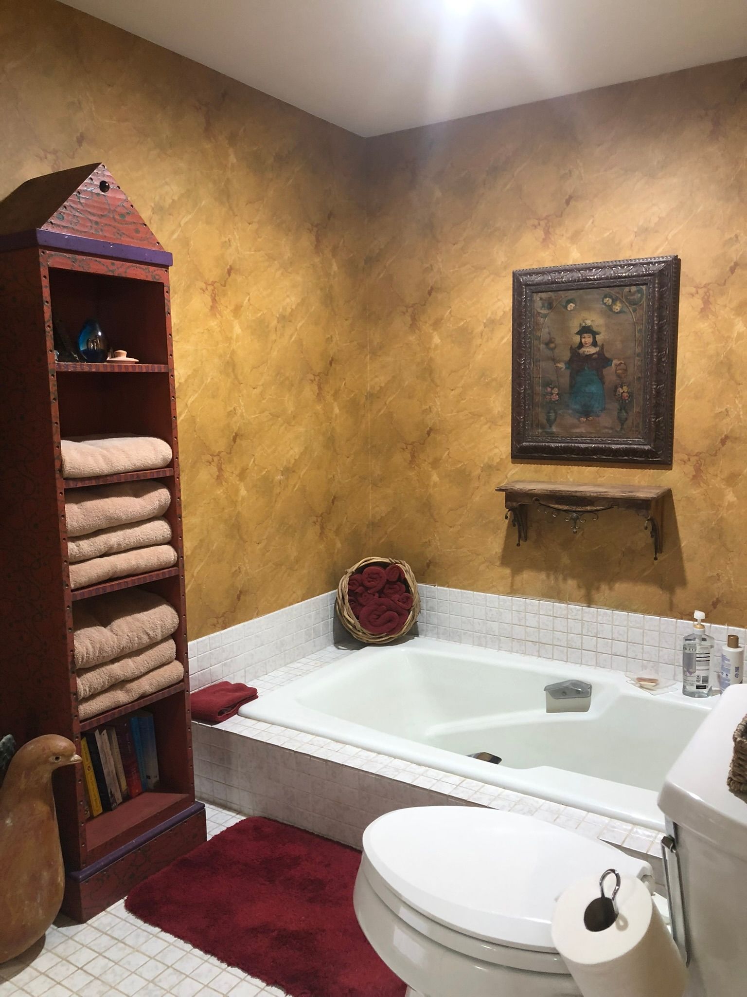 A bathroom with a tub , toilet , and a picture on the wall.