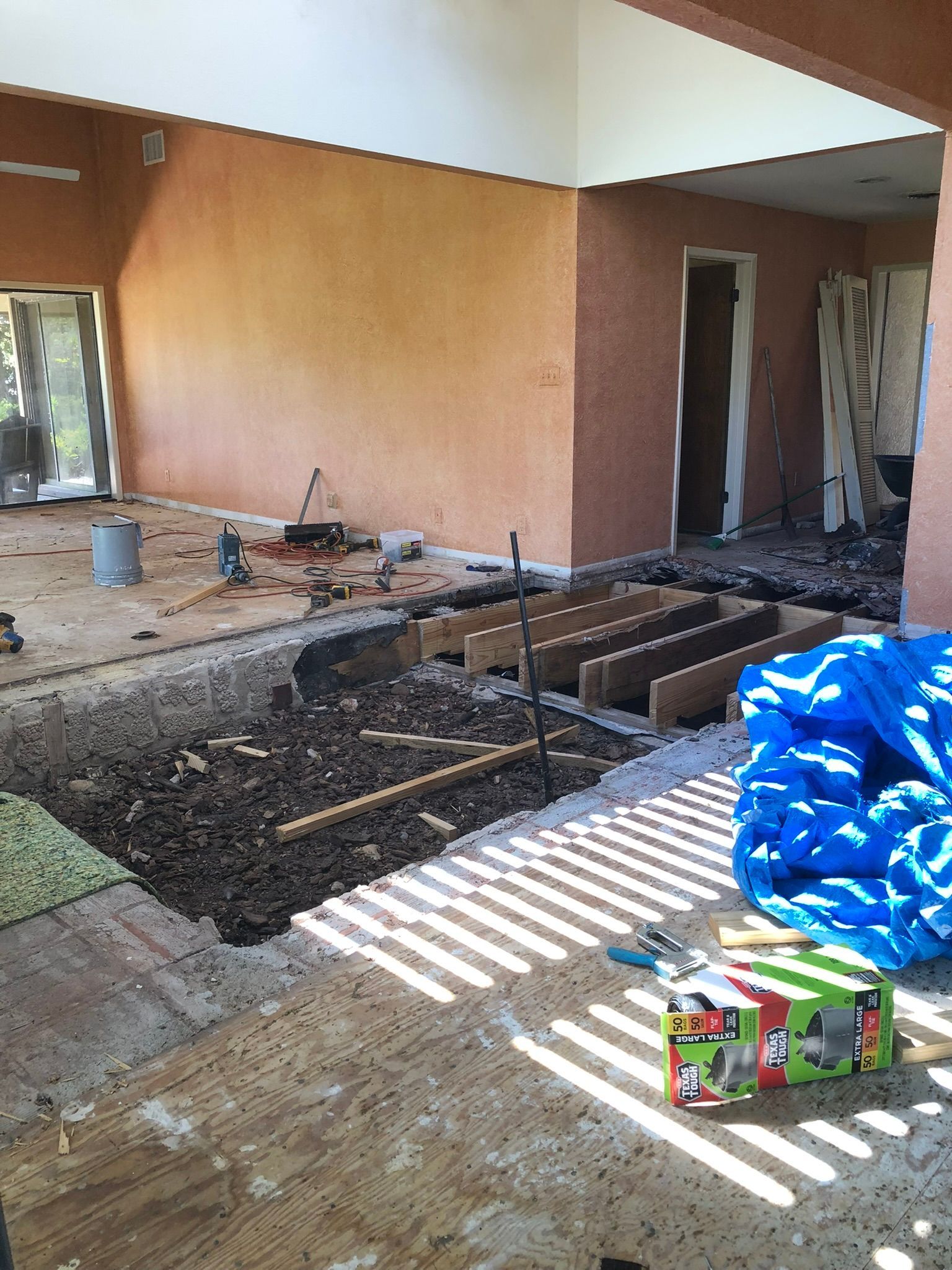 A room under construction with a blue tarp on the floor.