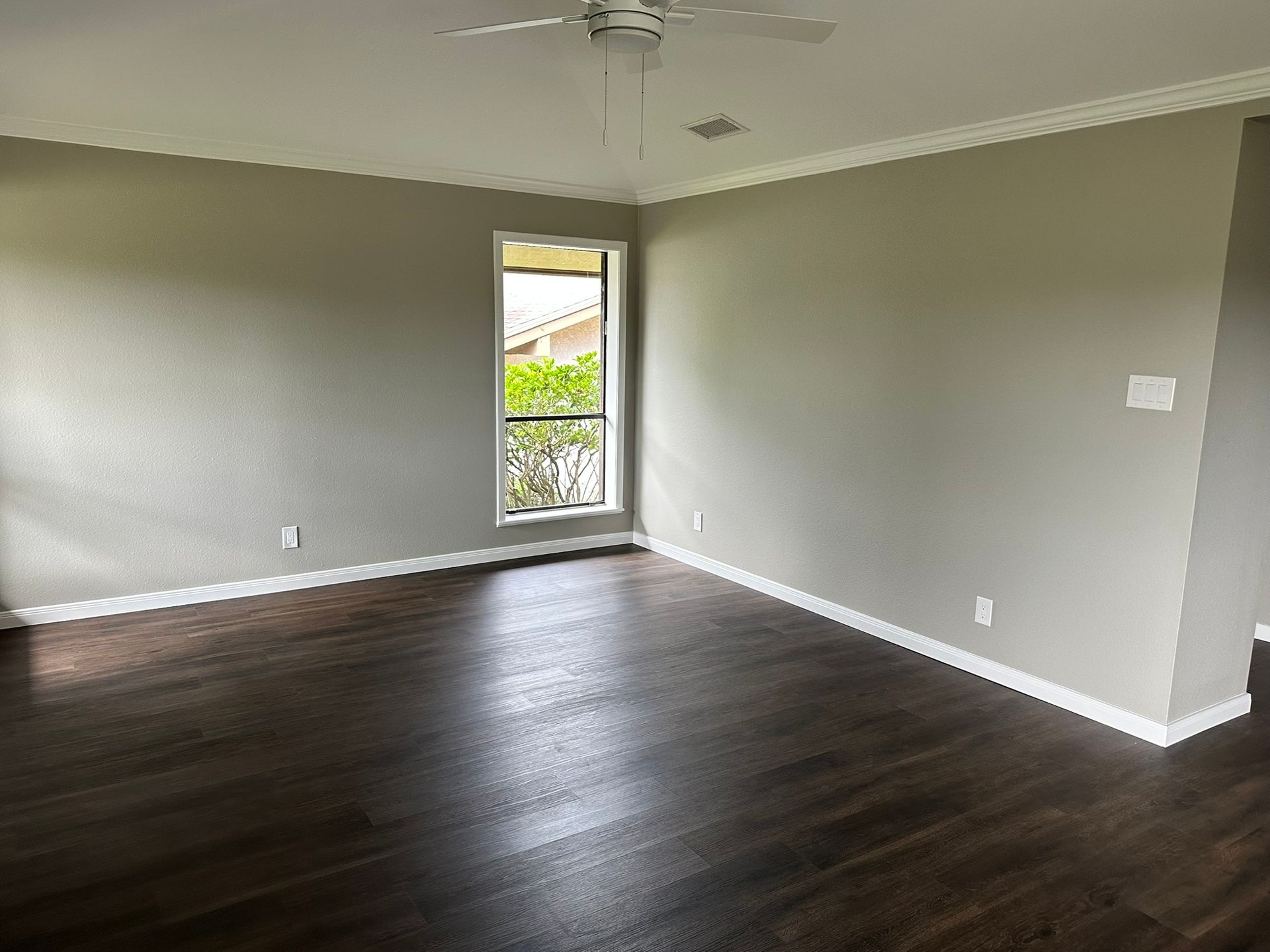 An empty living room with hardwood floors and a ceiling fan.