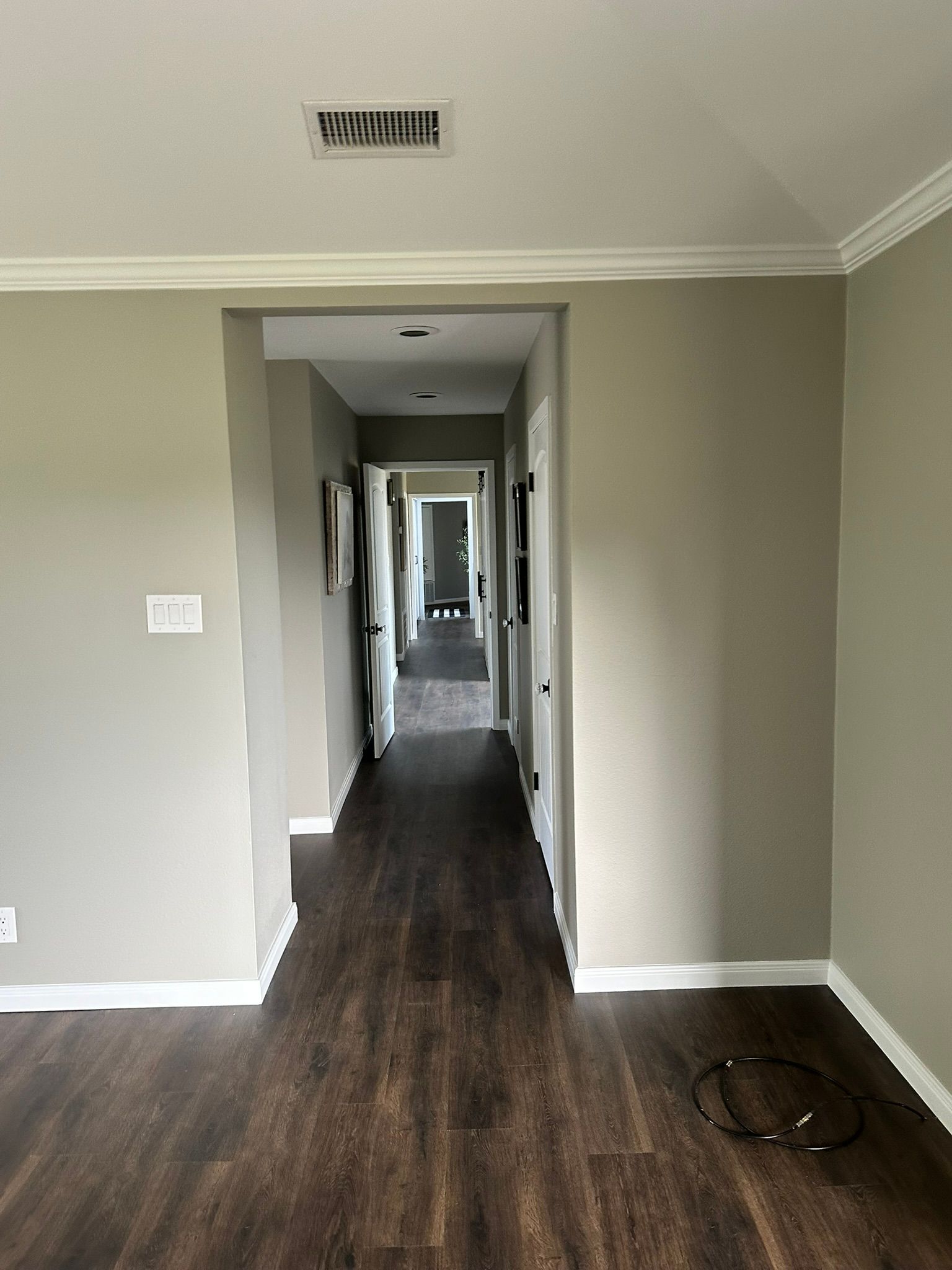 A long hallway in a house with hardwood floors and a ceiling fan.
