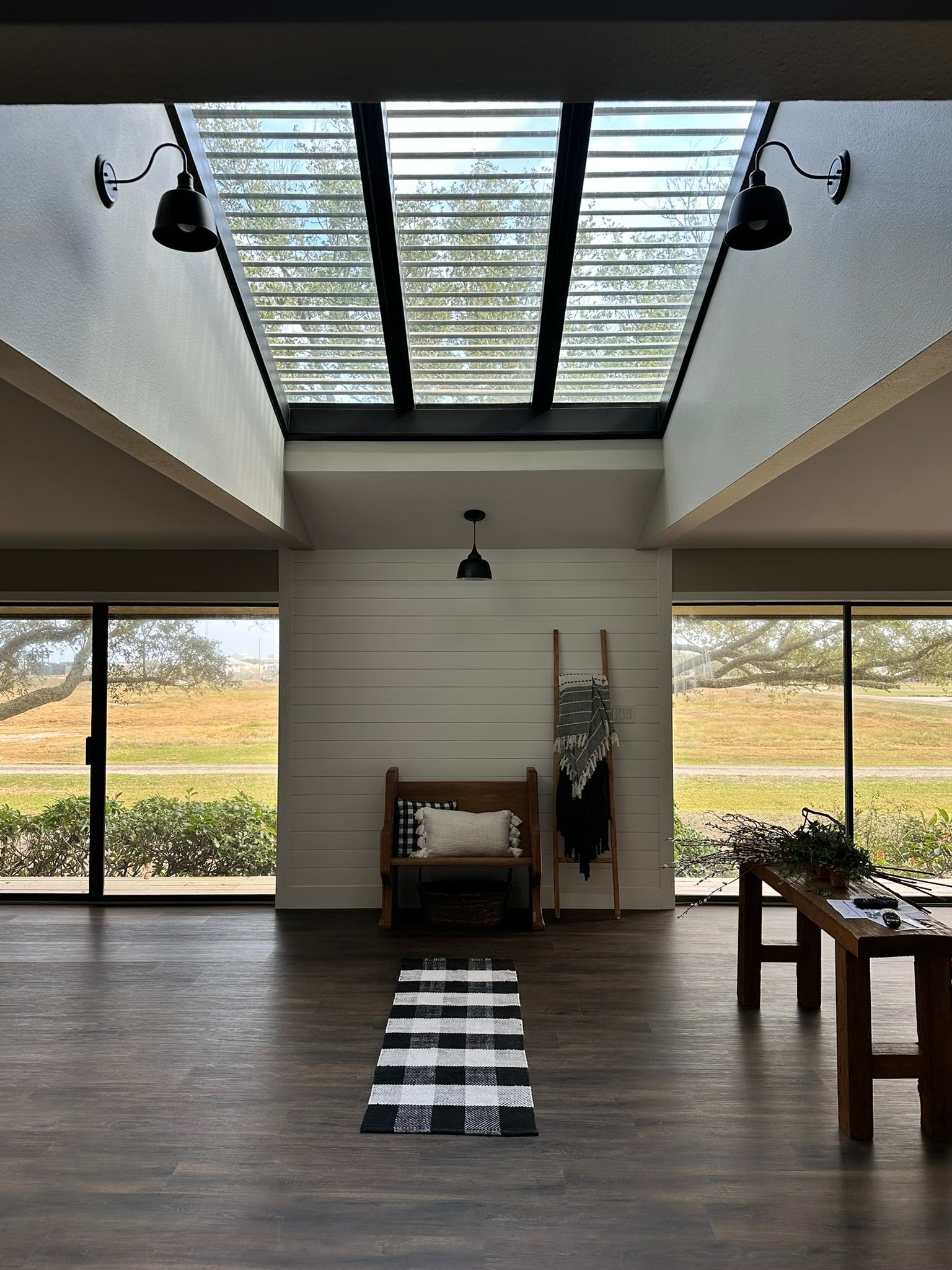 A living room with a skylight , a bench , a table and a rug.