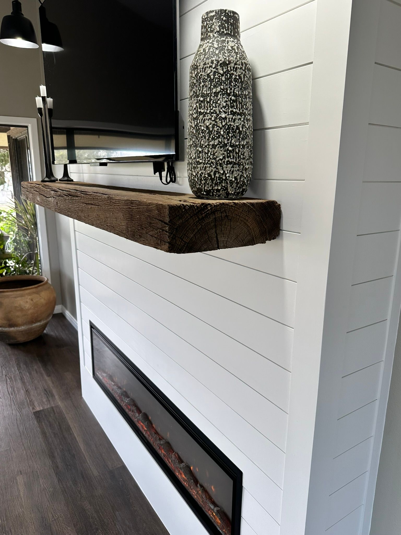 A fireplace with a tv on it and a vase on the mantle