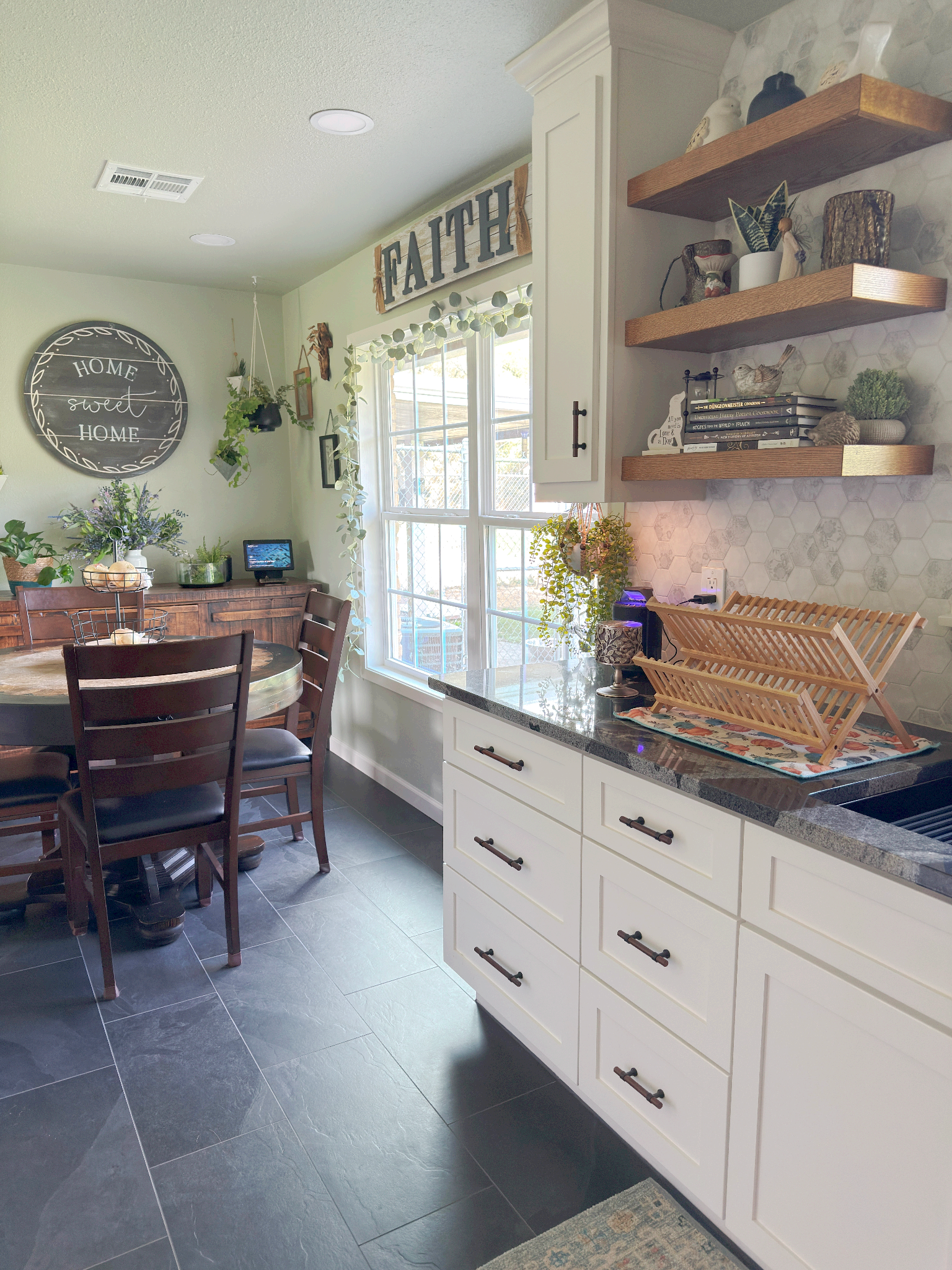 A kitchen with a table and chairs and a sign on the wall that says `` faith ''.