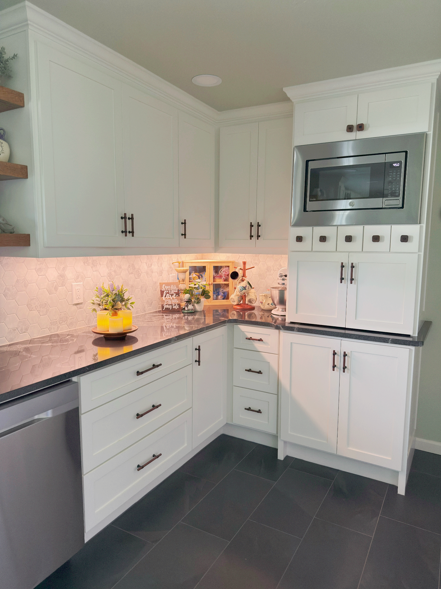 A kitchen with white cabinets , granite counter tops , stainless steel appliances and a microwave.