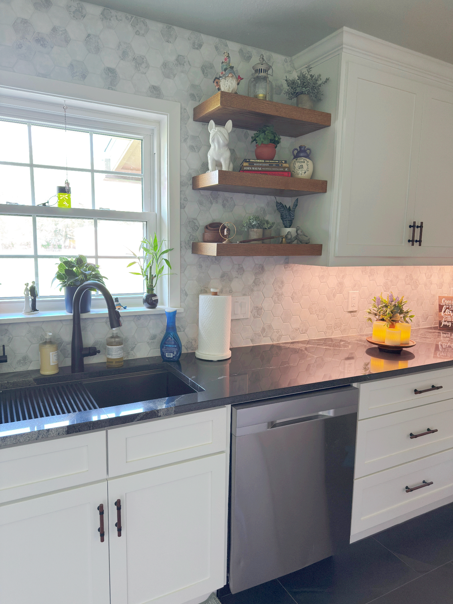 A kitchen with a sink , dishwasher , and shelves.