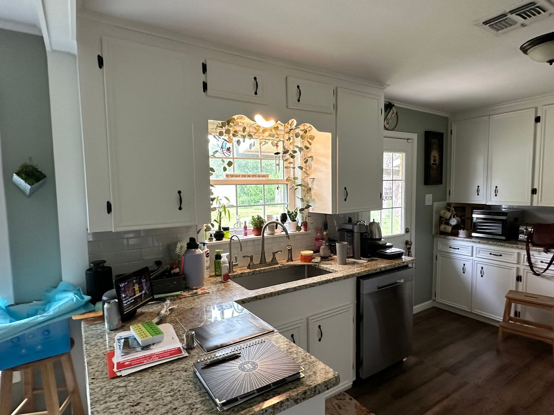 A kitchen with white cabinets , granite counter tops , a sink and a dishwasher.
