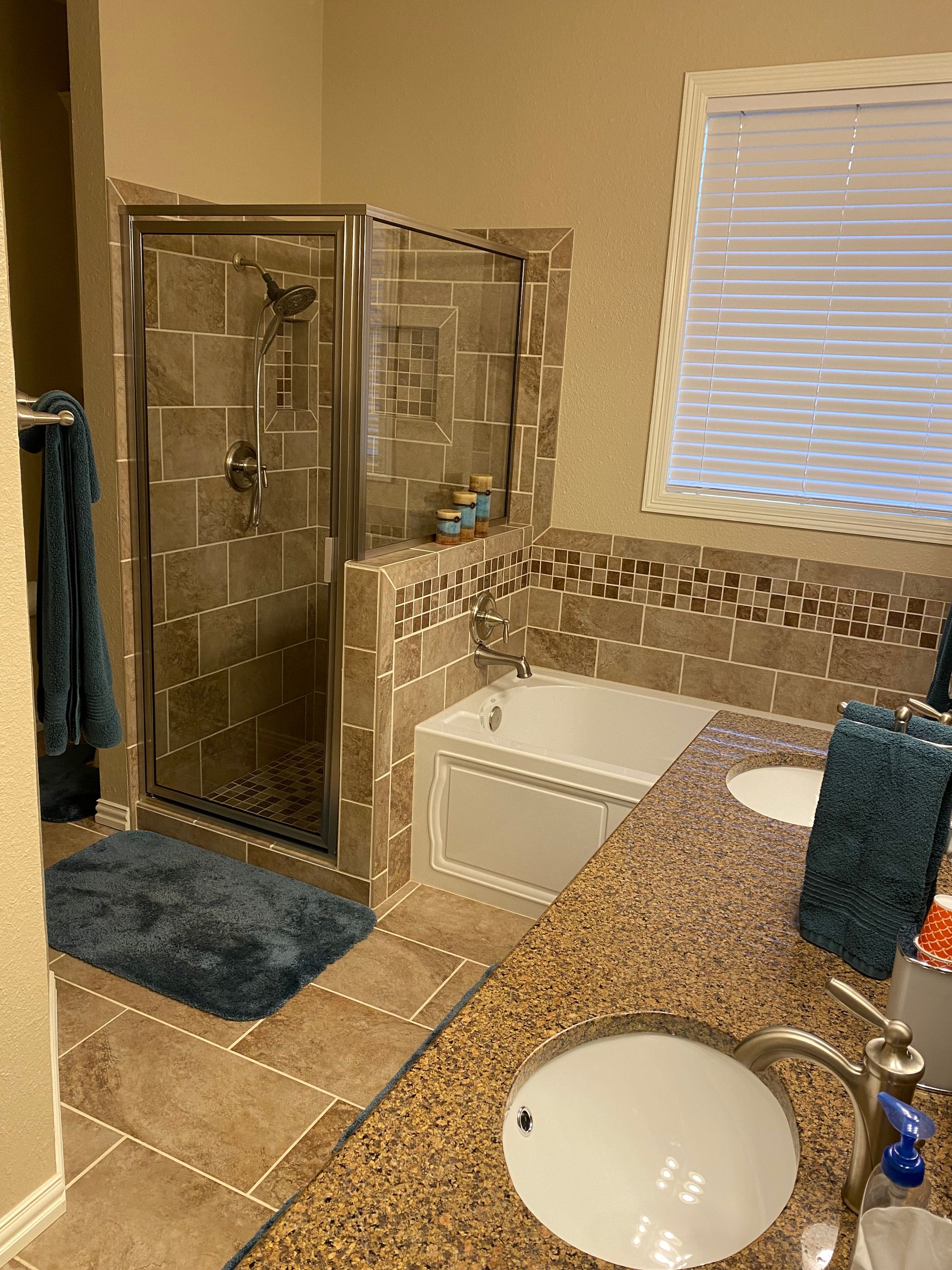 A bathroom with a sink , tub , shower and window.