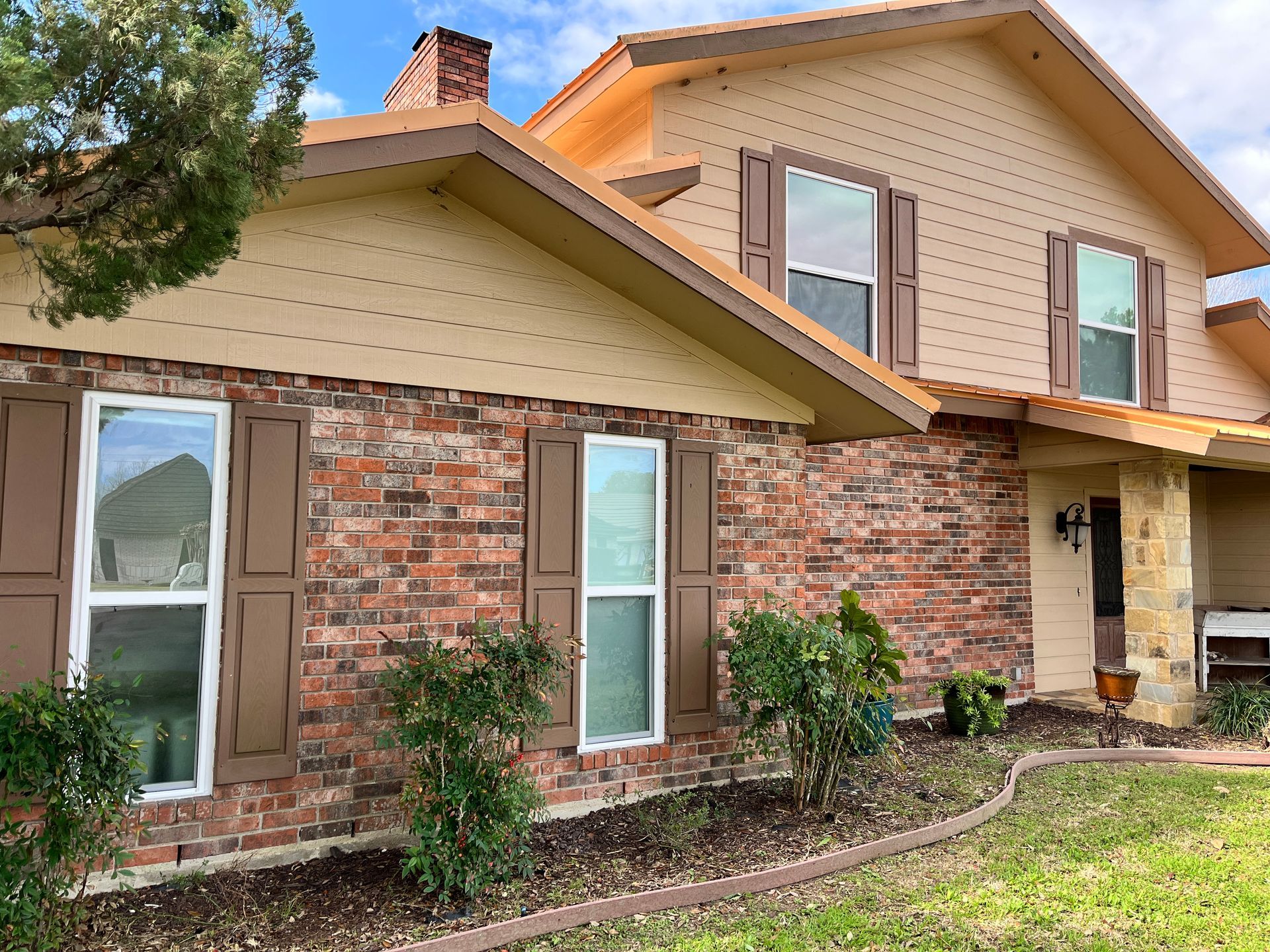A large brick house with brown shutters on the windows