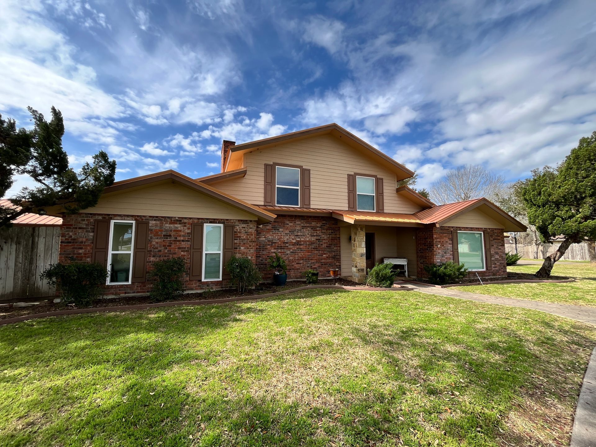 A large brick house with a lush green lawn in front of it.