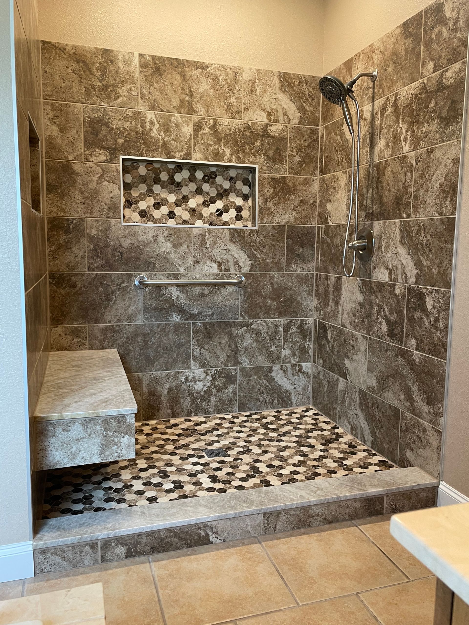 A walk in shower with a bench and a shower head.