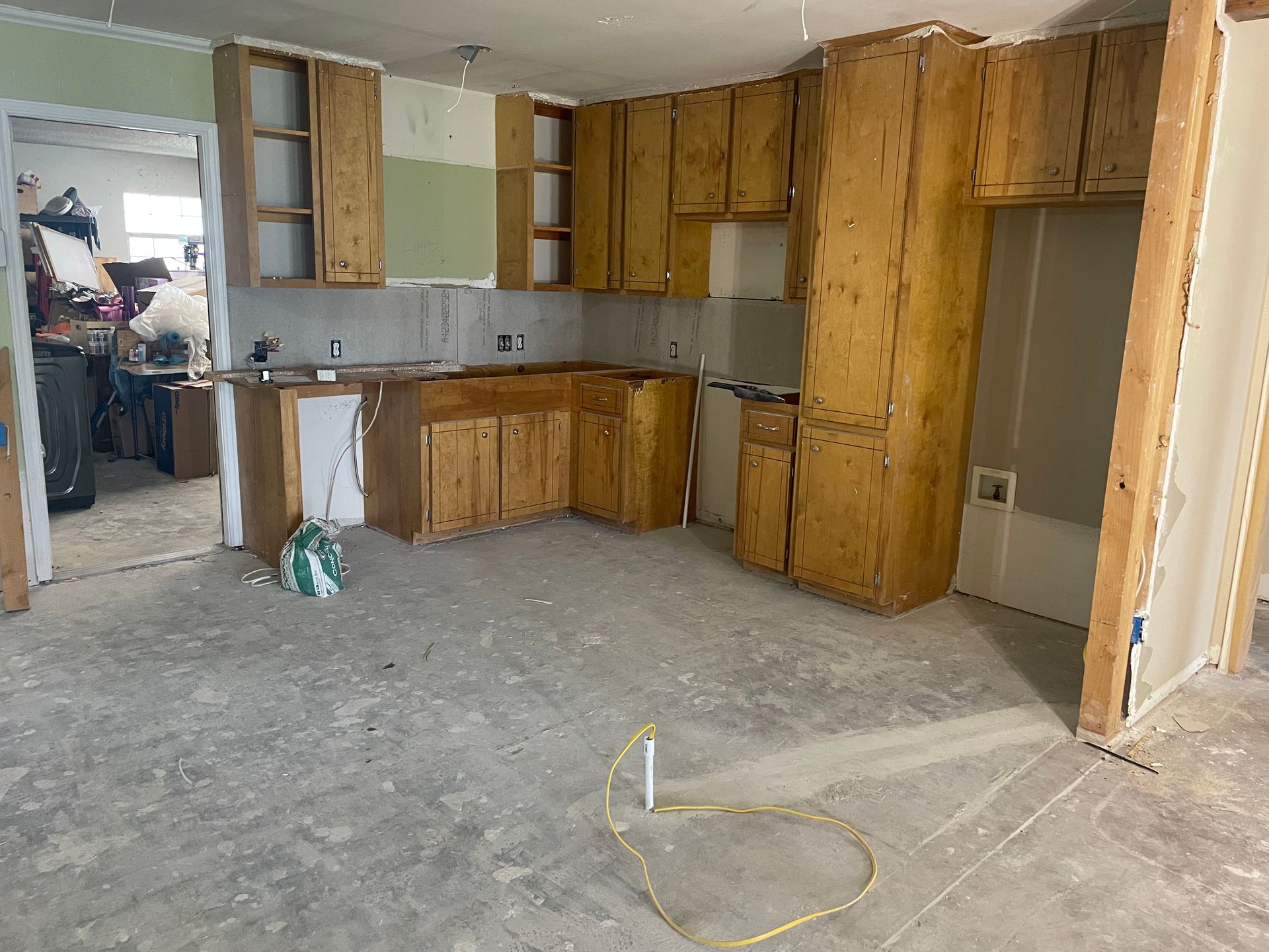 A kitchen with wooden cabinets and a concrete floor is being remodeled.