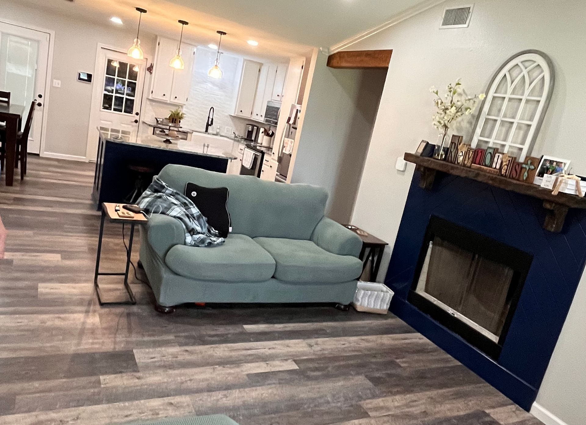 A living room with a blue couch and a fireplace.