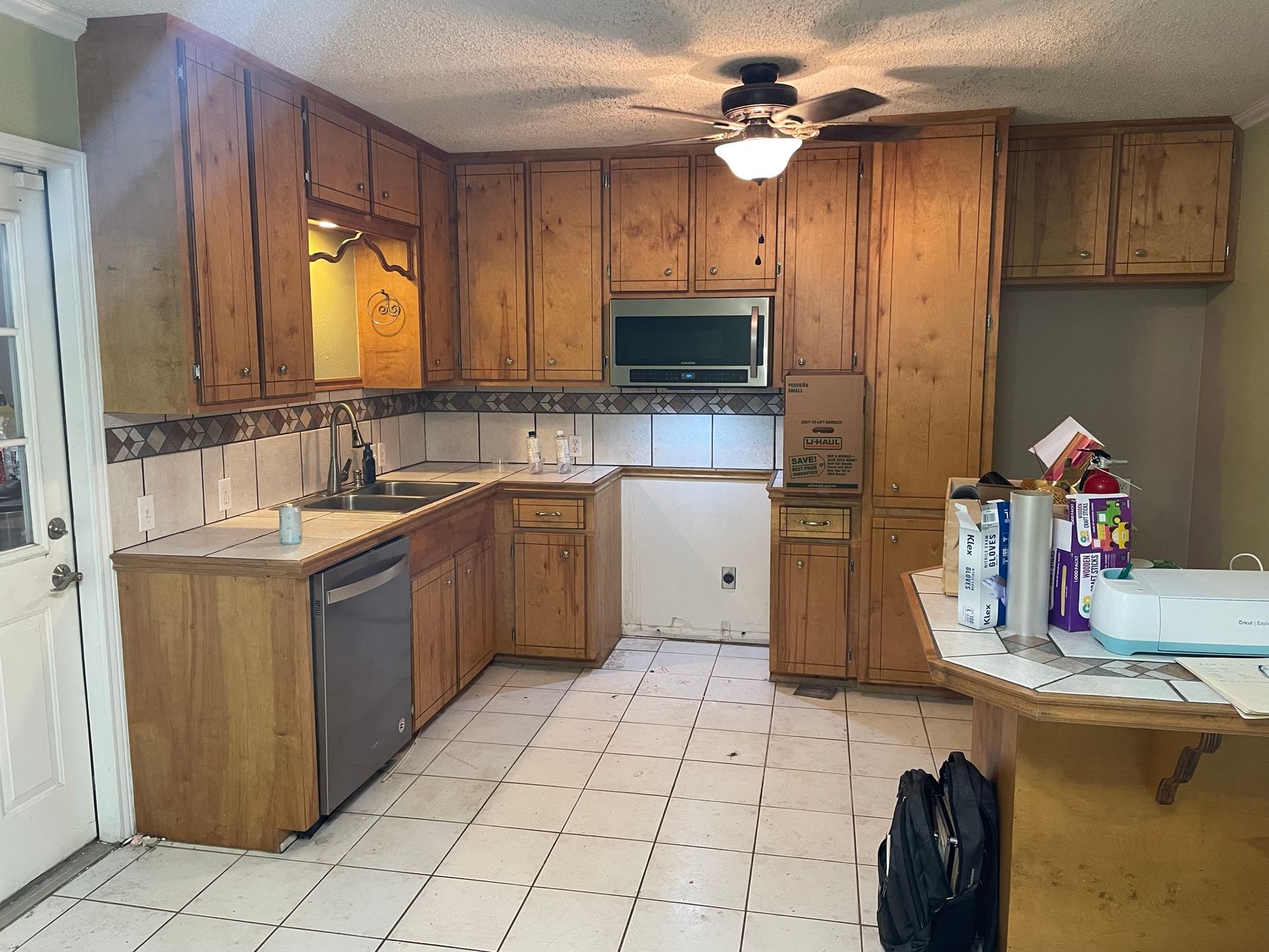 A kitchen with wooden cabinets and a ceiling fan