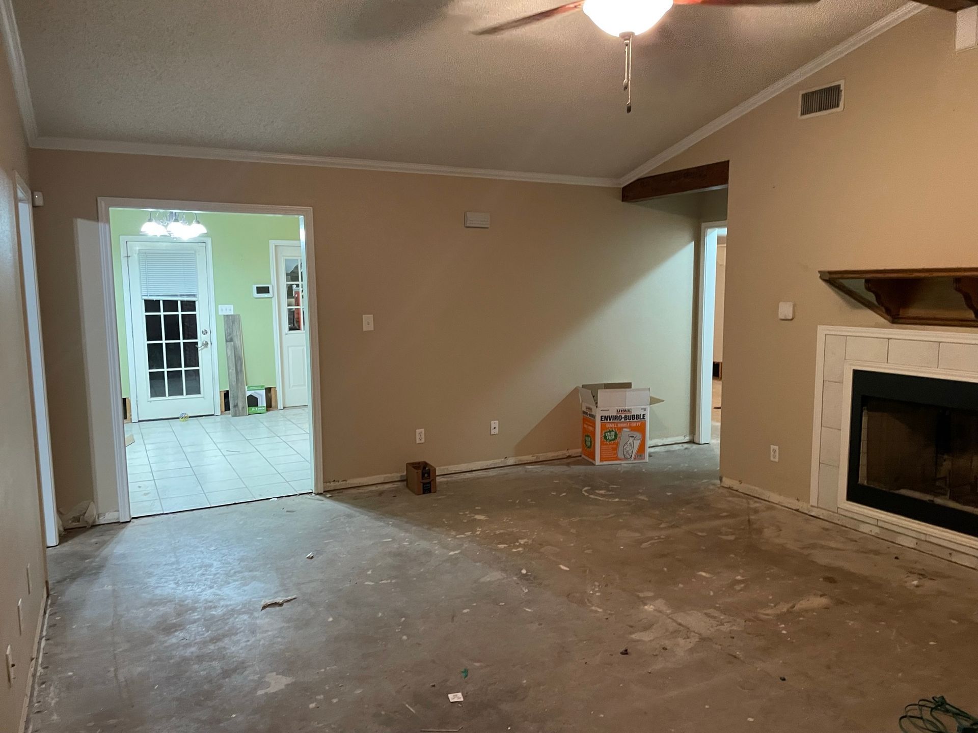 An empty living room with a fireplace and a ceiling fan.