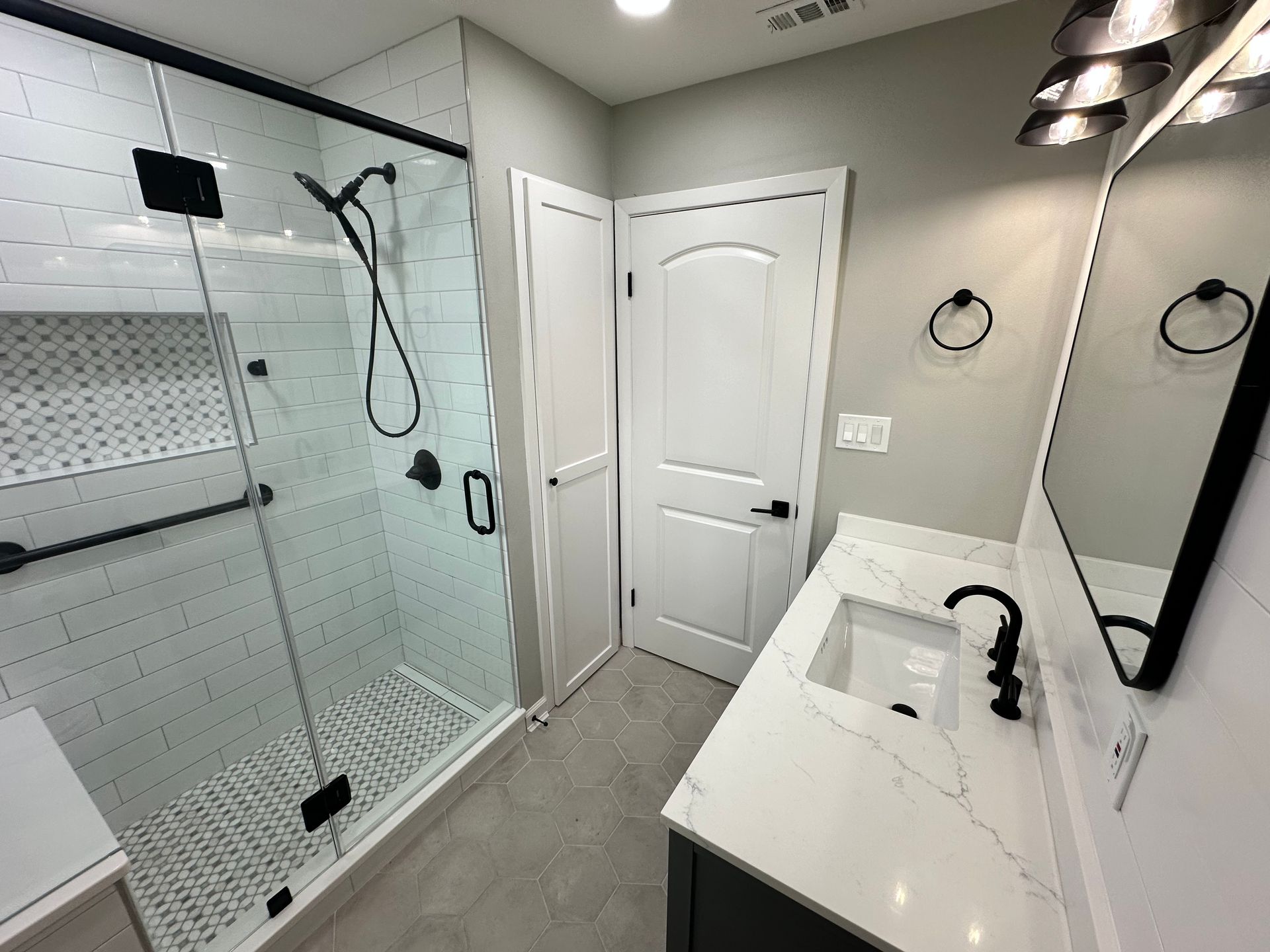 A bathroom with a walk in shower , sink and mirror.
