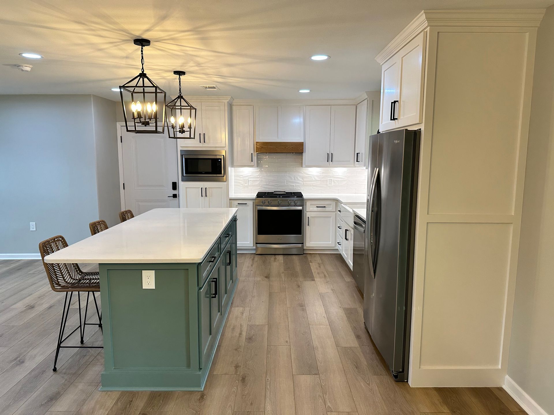 A kitchen with white cabinets , stainless steel appliances , and a large island.