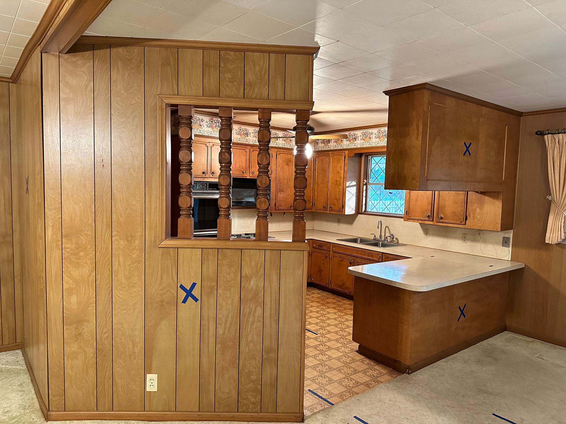 A kitchen with wood paneling and a blue x on the wall