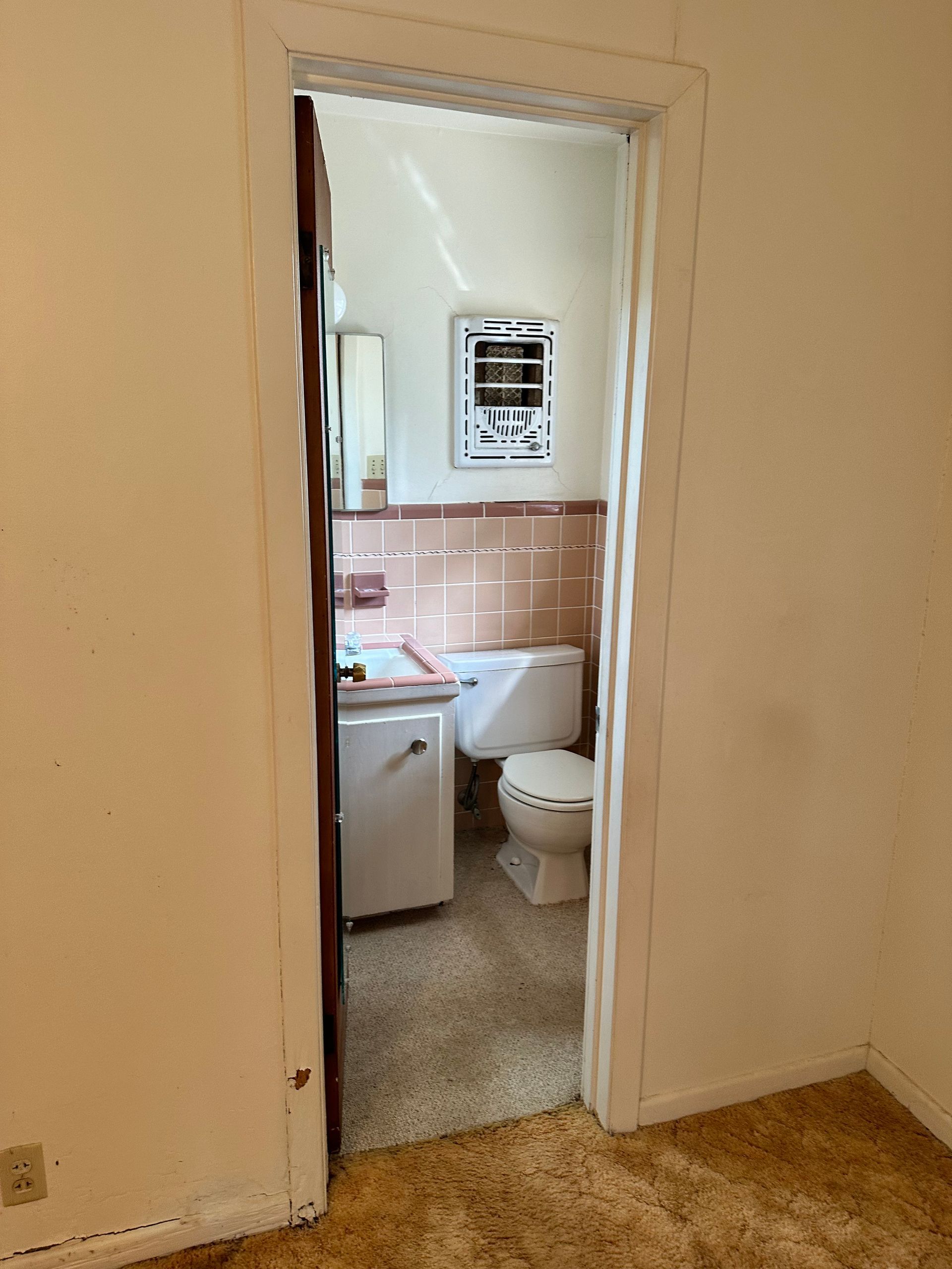 A bathroom with a toilet , sink and mirror.