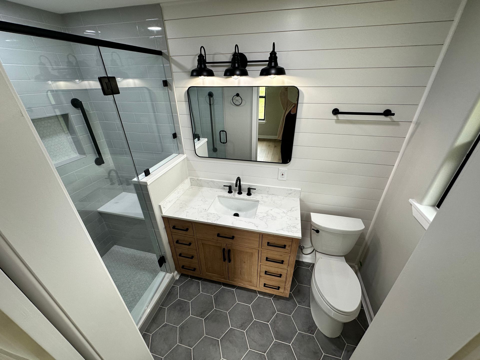 A bathroom with a sink , toilet , shower and mirror.