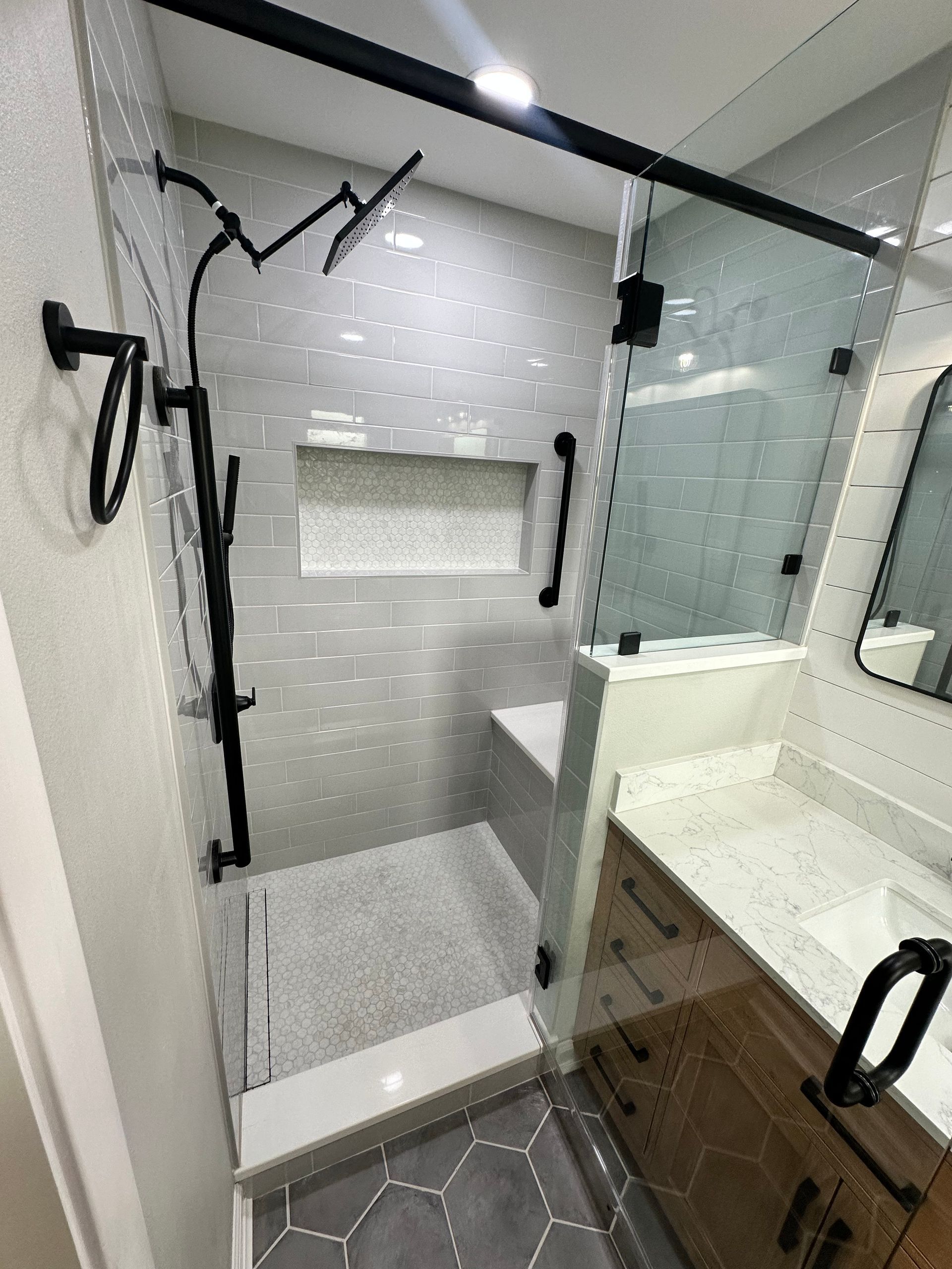 A bathroom with a walk in shower and a sink.