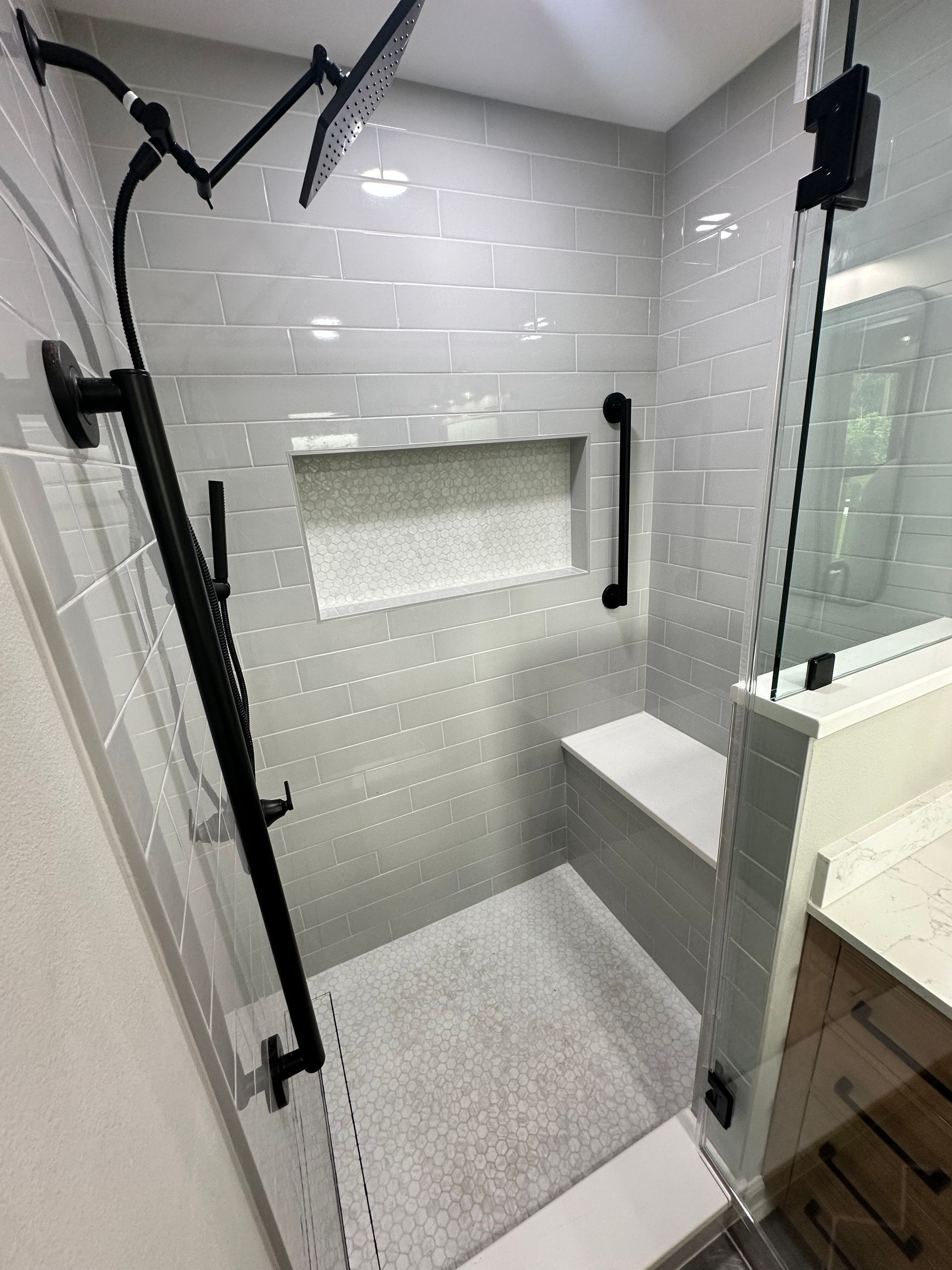 A bathroom with a walk in shower and a bench.