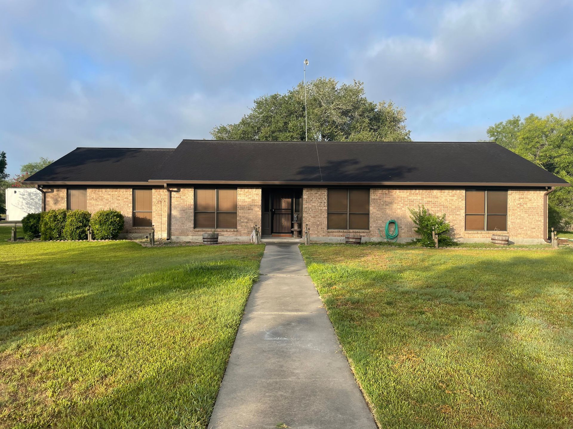 A brick house with a black roof and a walkway leading to it.