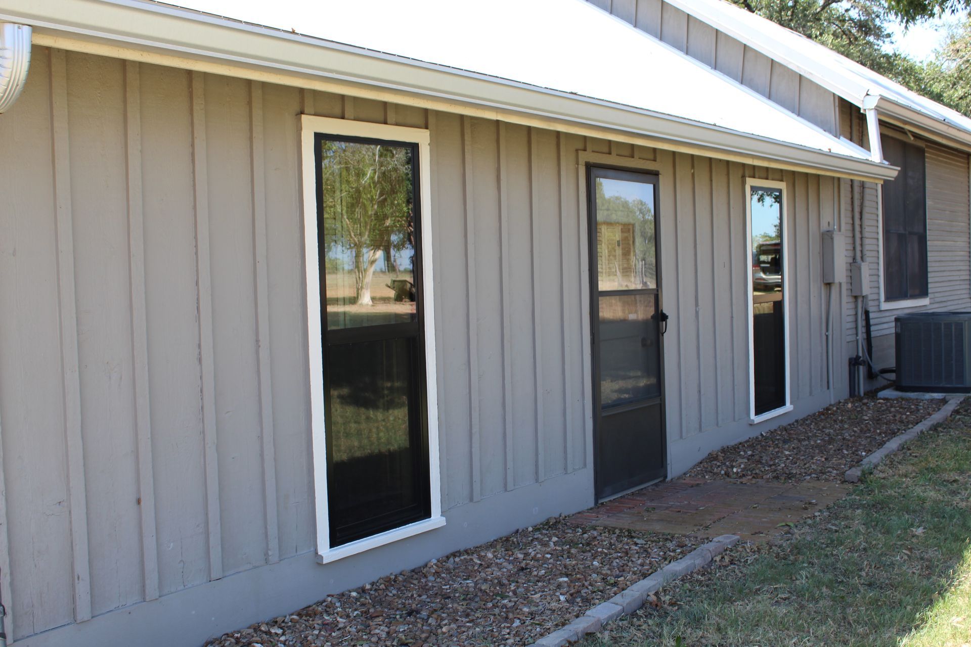 A gray house with black windows and a white roof.