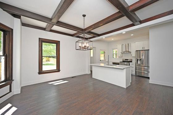 A kitchen and dining room in an empty house with wooden beams
